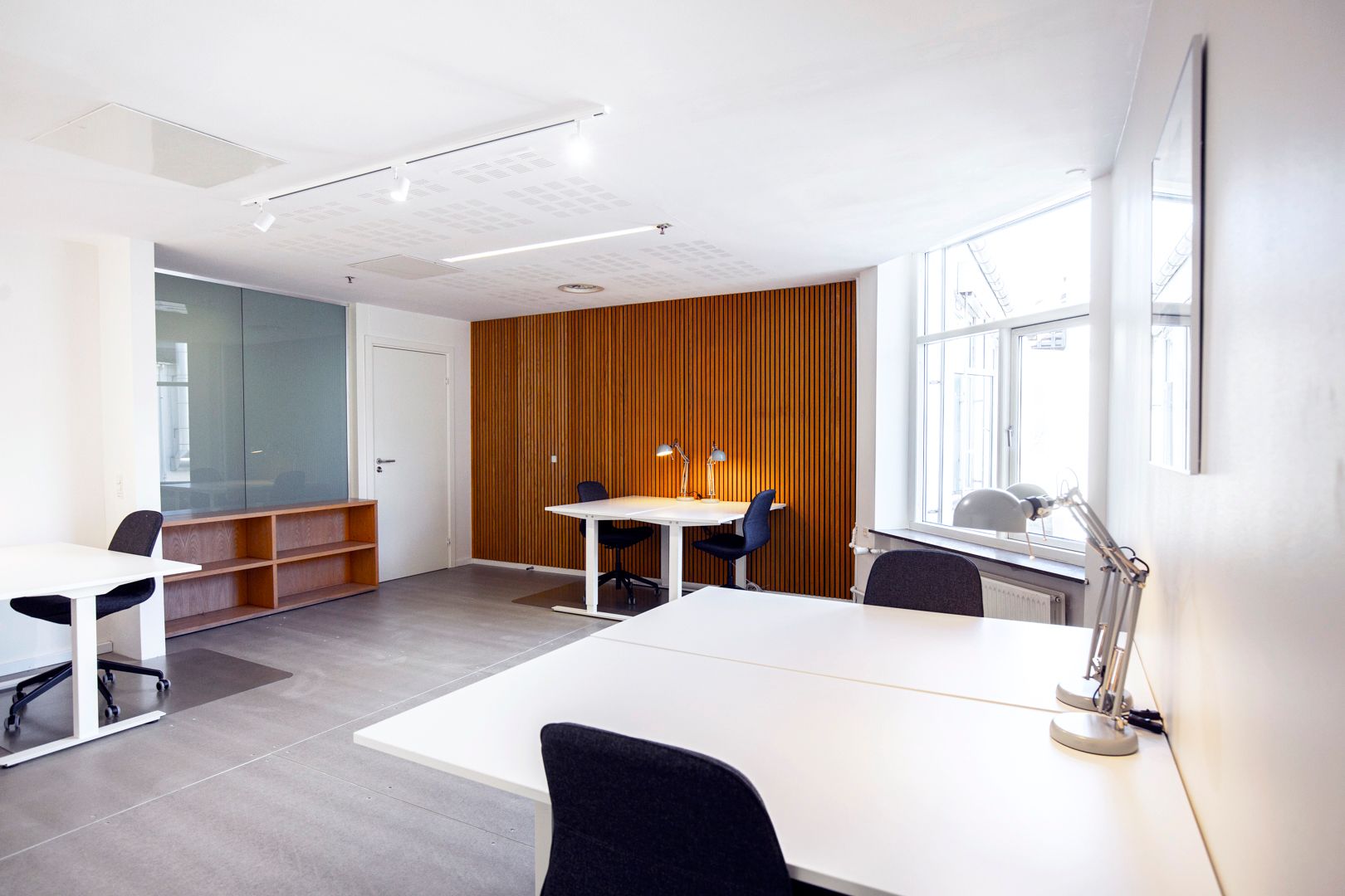 Kontorrum med hvide borde, lyse trævægge og moderne møbler for at skabe en professionel og indbydende arbejdsplads