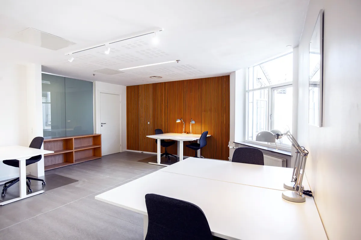 Kontorrum med hvide borde, lyse trævægge og moderne møbler for at skabe en professionel og indbydende arbejdsplads