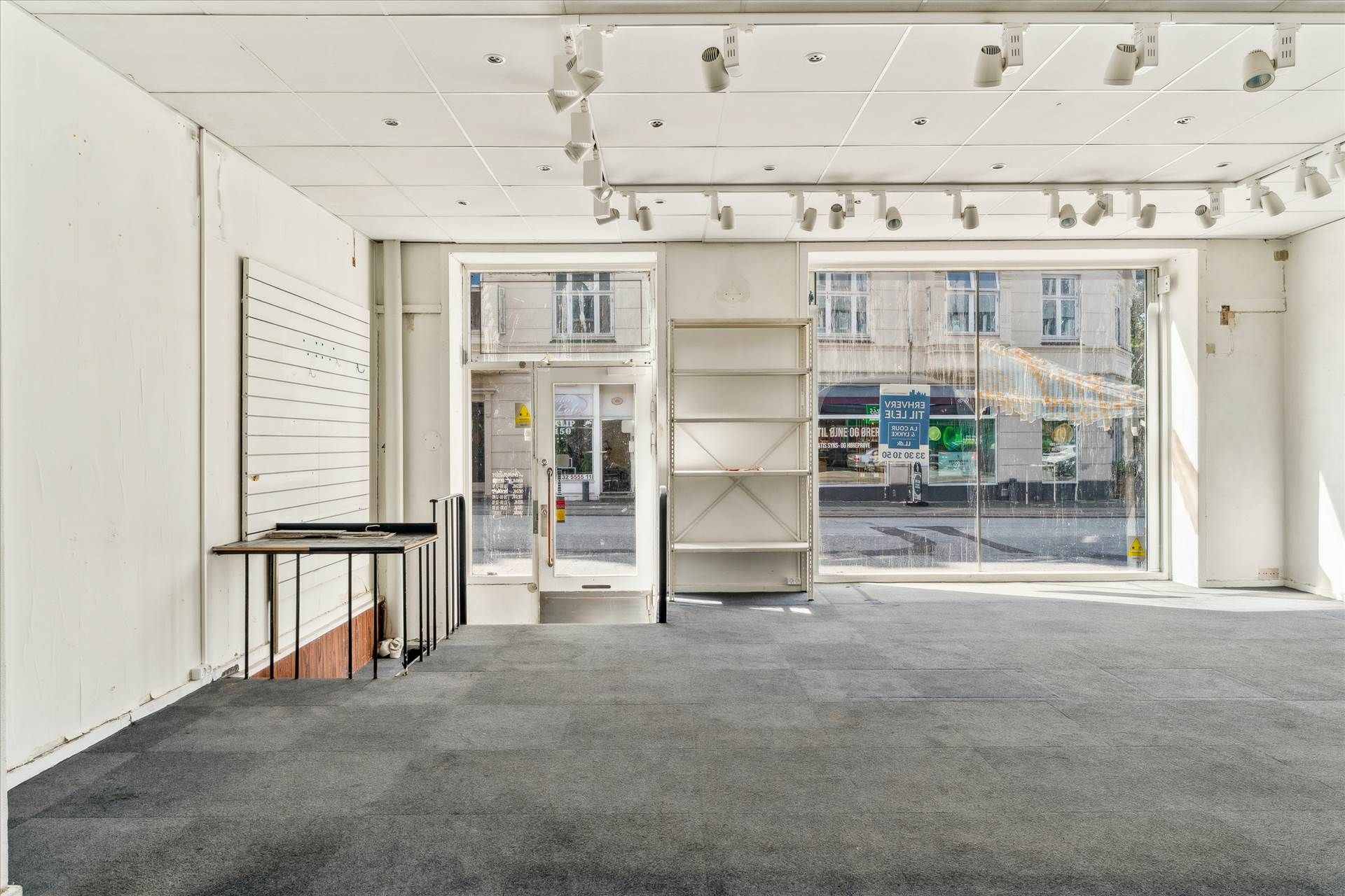 Store, tomt erhvervslejemål med vinduer og indgangsdøre i en bygning med hvidt interiør og gulvbelægning