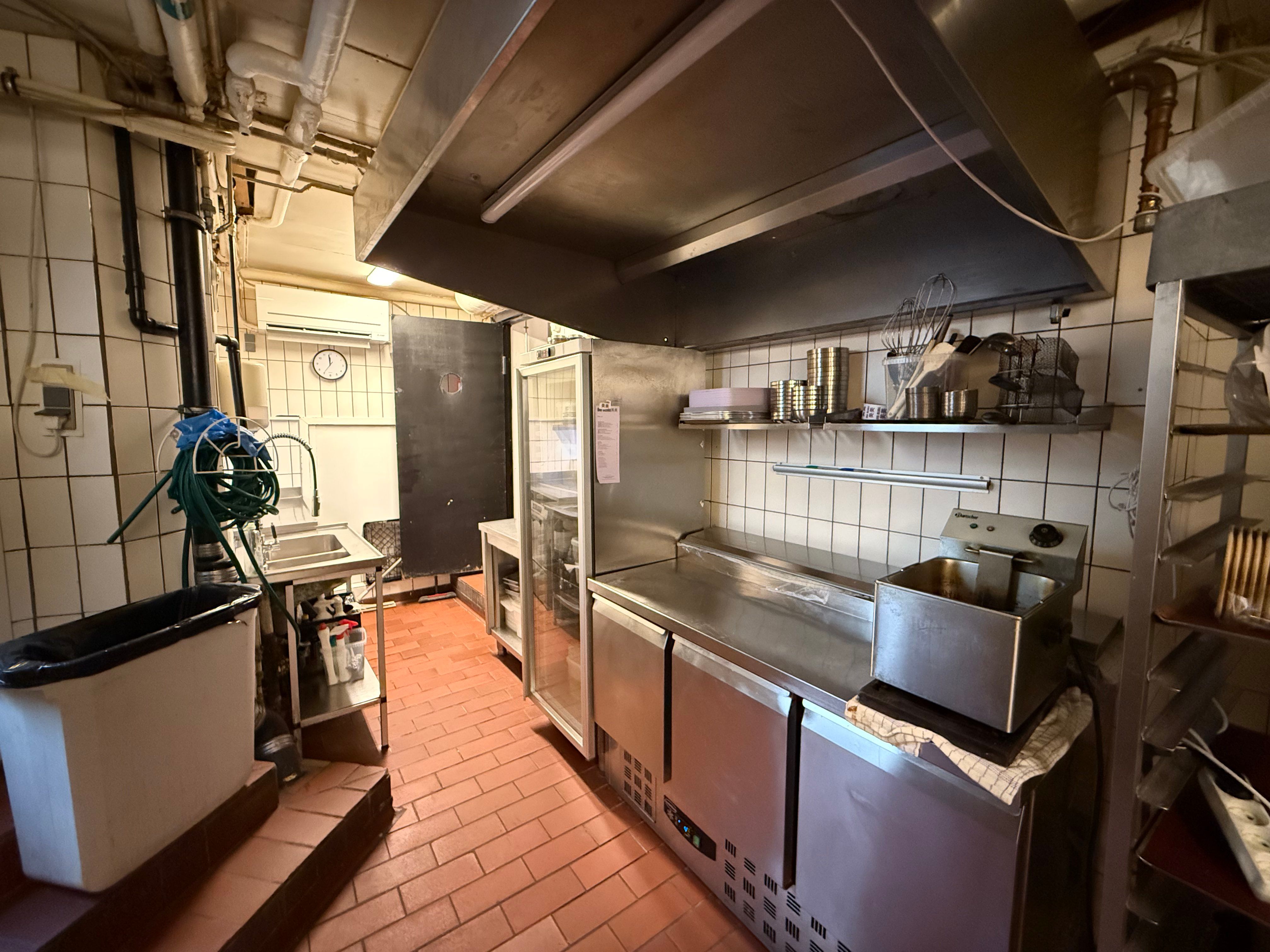 Køkken med flere apparater og opbevaringsskuffer samt metalbord, der er dækket med en klud