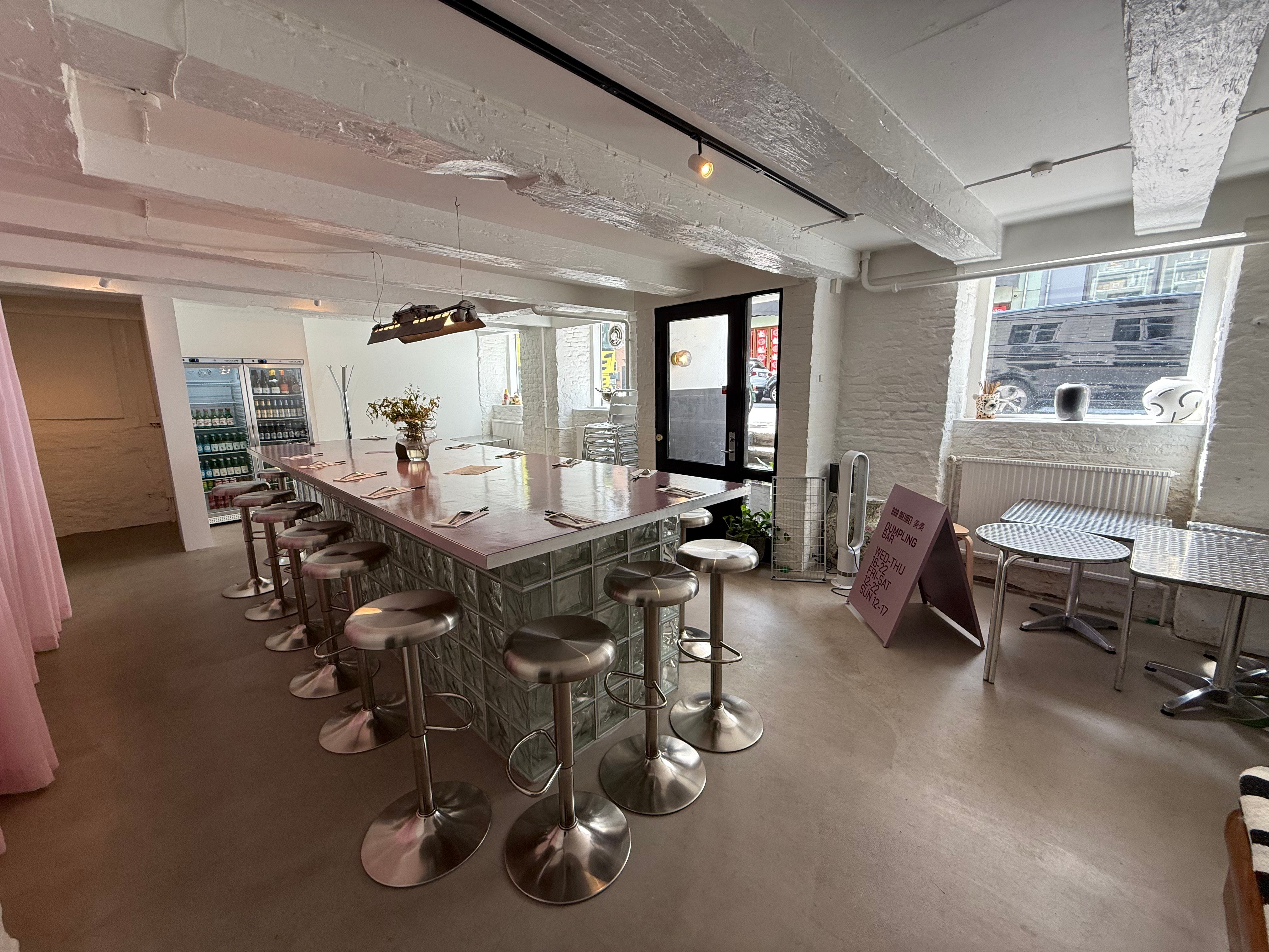 En slank restaurant med høje stole og et bord, hvor der står et bord med en vase med blomster og tæppet på gulvet