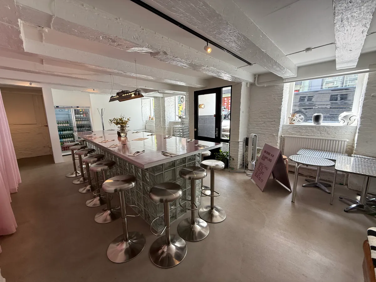 En slank restaurant med høje stole og et bord, hvor der står et bord med en vase med blomster og tæppet på gulvet