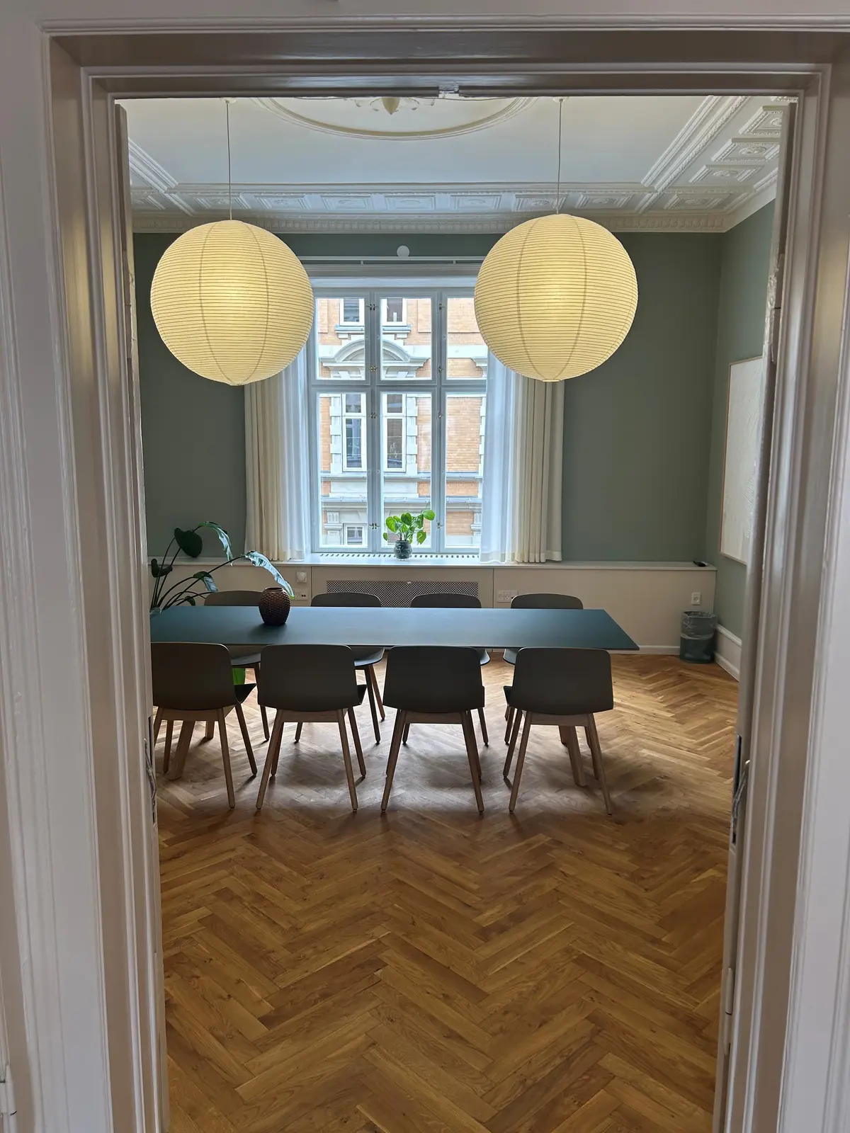 Her ses et herskabslejlighed med smagfuldt indrettet spisestuen. Lyse, lysegrå vægge og lysegule loftslamper giver et