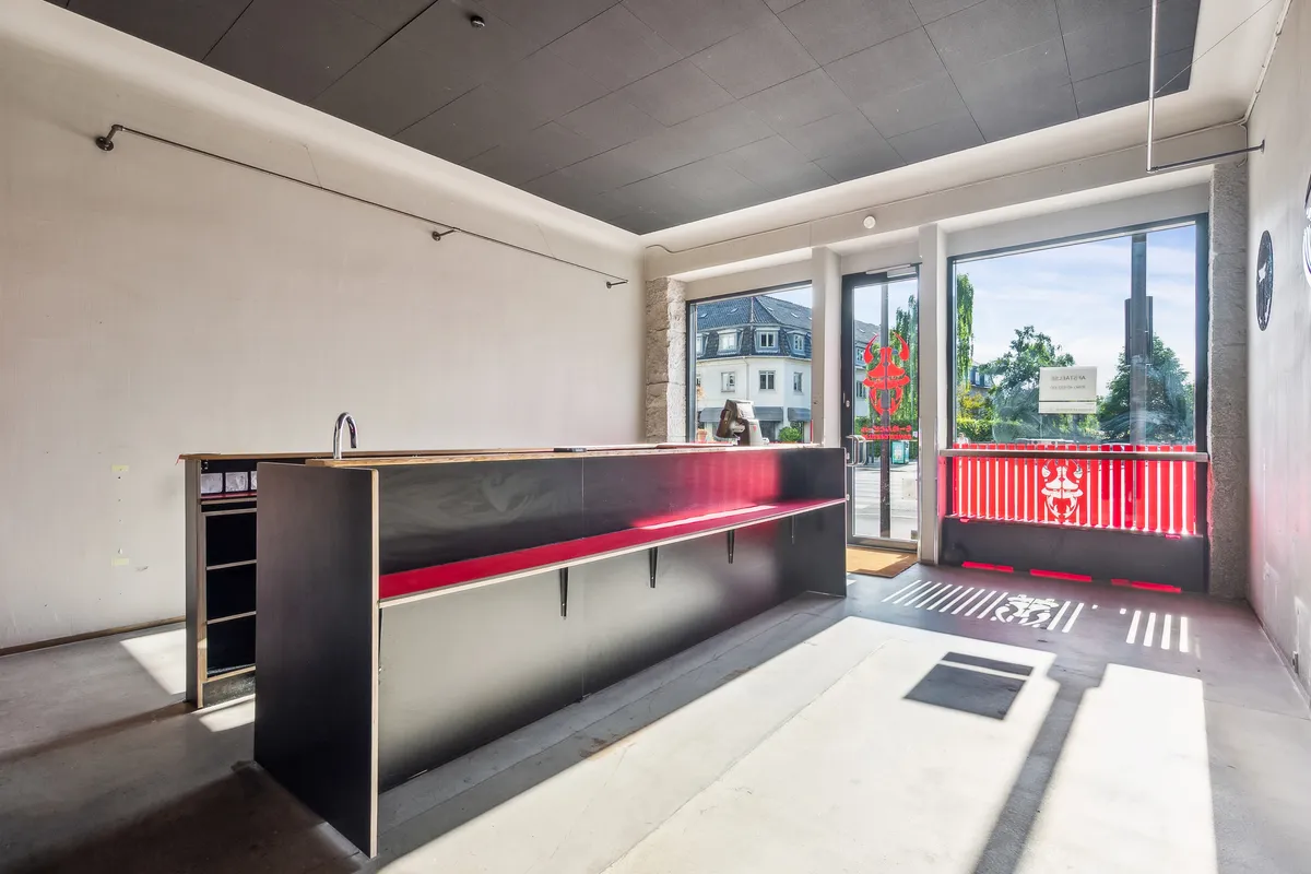 Solsiden på Strandvejen i Hellerup med indgang til restaurant med røde stolpe og rødt mønster på vinduet