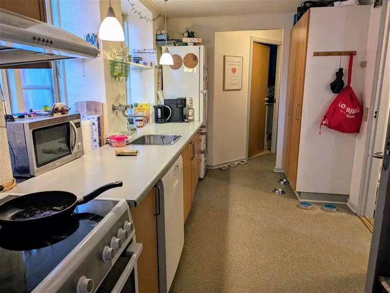 En moderne køkken med en ovn, komfur, vaskebækken og en køleskab med flere ting på den. Der er også en mikroovn og et