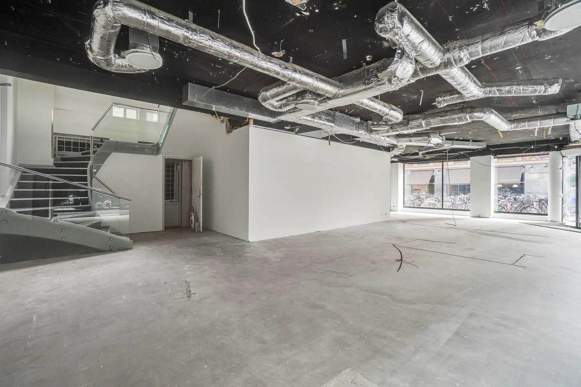 Stort, tomt lokale med højt til loftet og lysevinduer til siderne og bagved