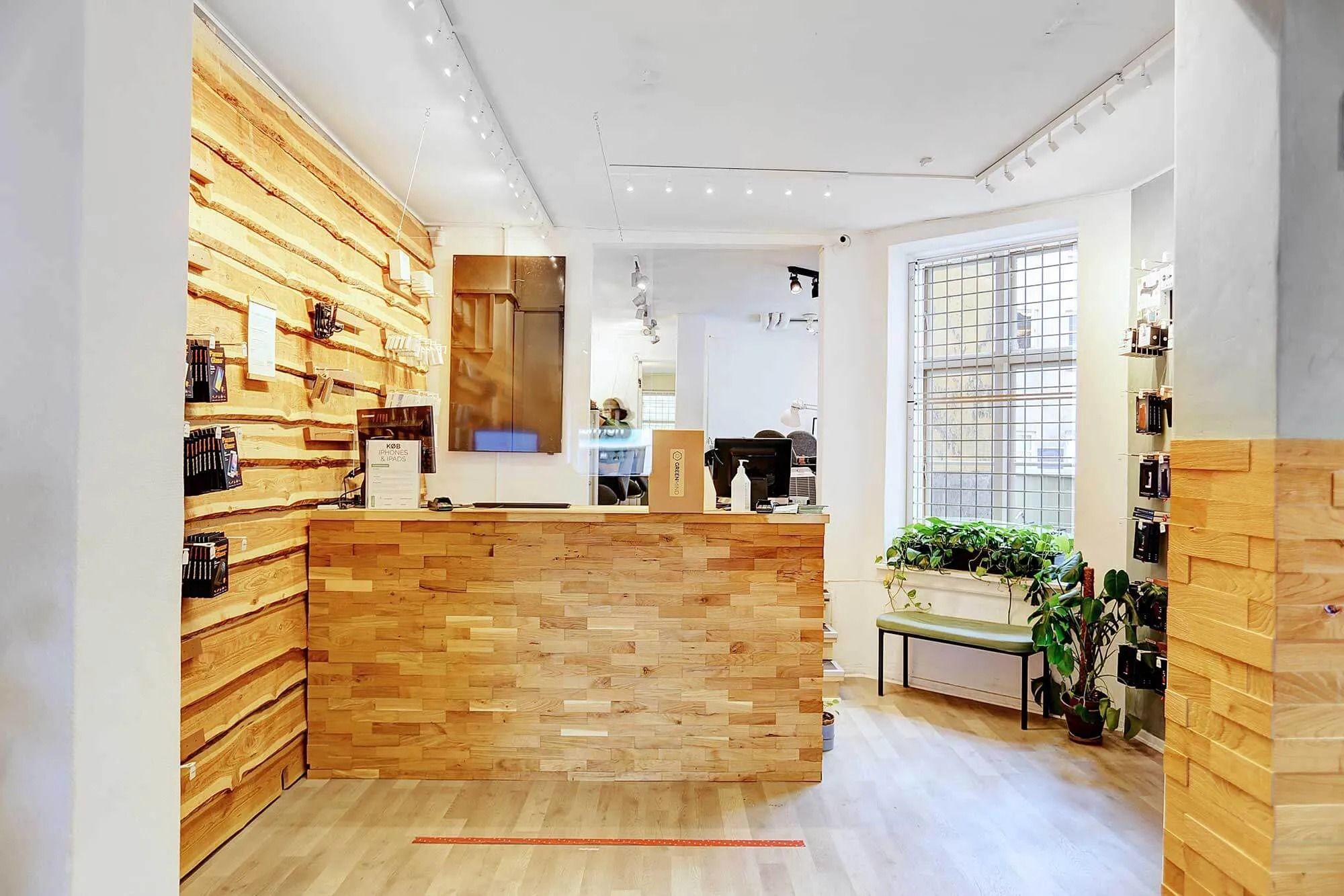 En træpaneleret lobby med en reception og en stor plante samt en udsigt til en bygade