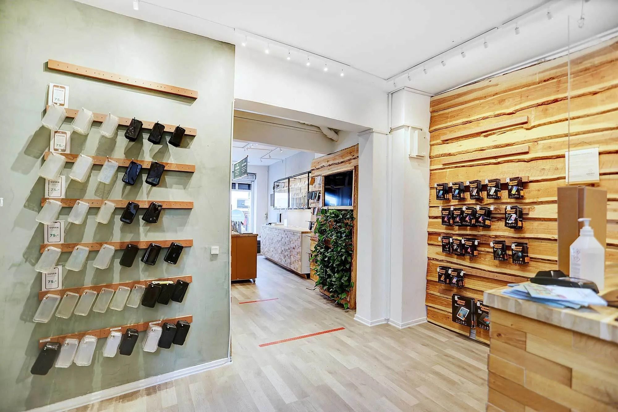 Købmagergade med en butik med hvide og lysegrå vægge og træindslag på væggene og hjørneskabsmøbler og gulv med produkter