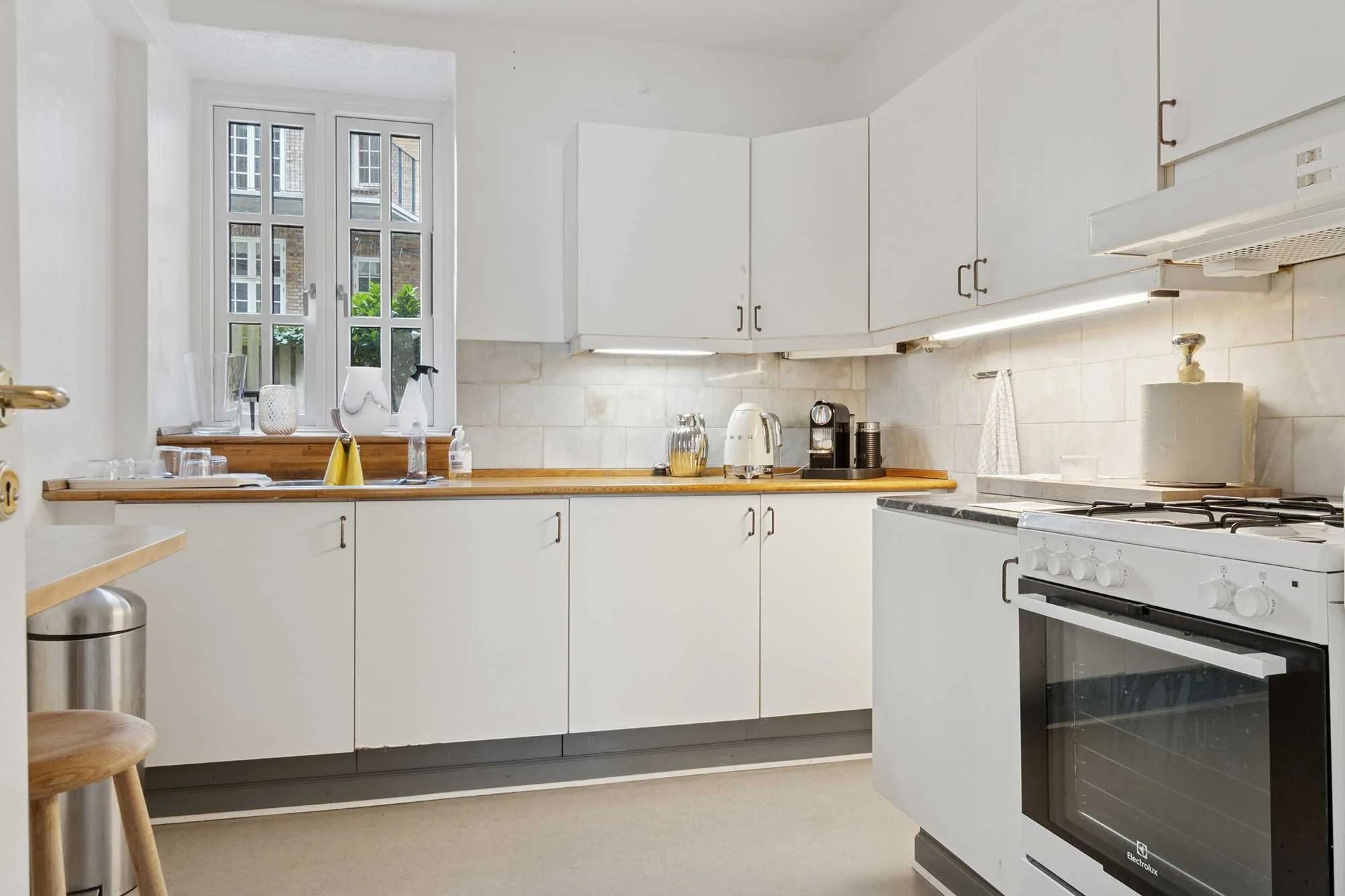 En moderne og funktionel køkken med hvide skabsfronter, en spisestue med et bord og stol, og lysegule vægge