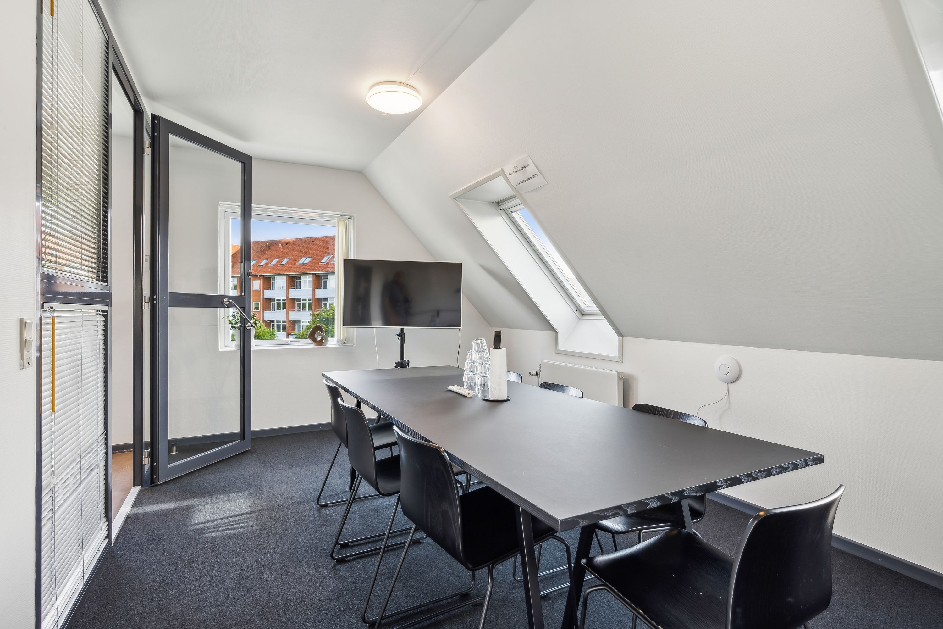 Kontorværelse med møbler og teknologi til møder. Lys og moderne interiør med lyse gulve og hvide vægge. Langt skrivebord med