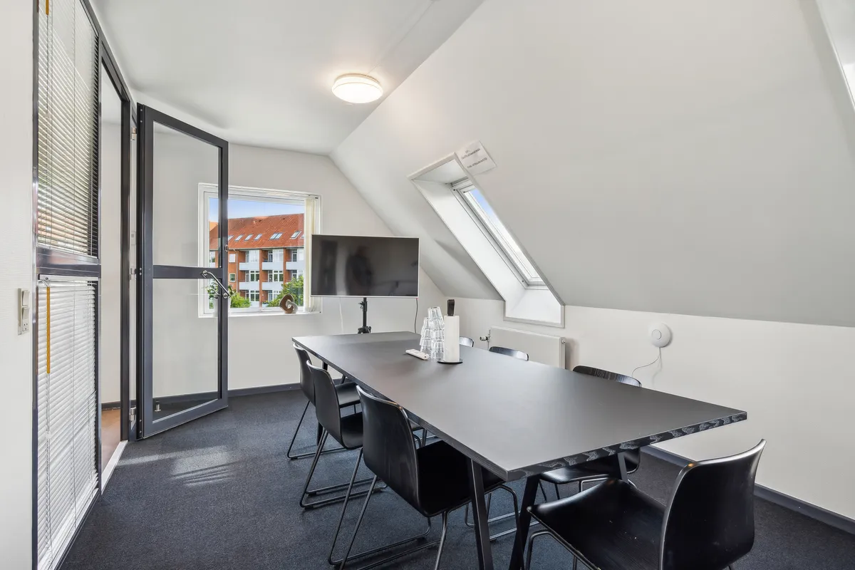 Kontorværelse med møbler og teknologi til møder. Lys og moderne interiør med lyse gulve og hvide vægge. Langt skrivebord med