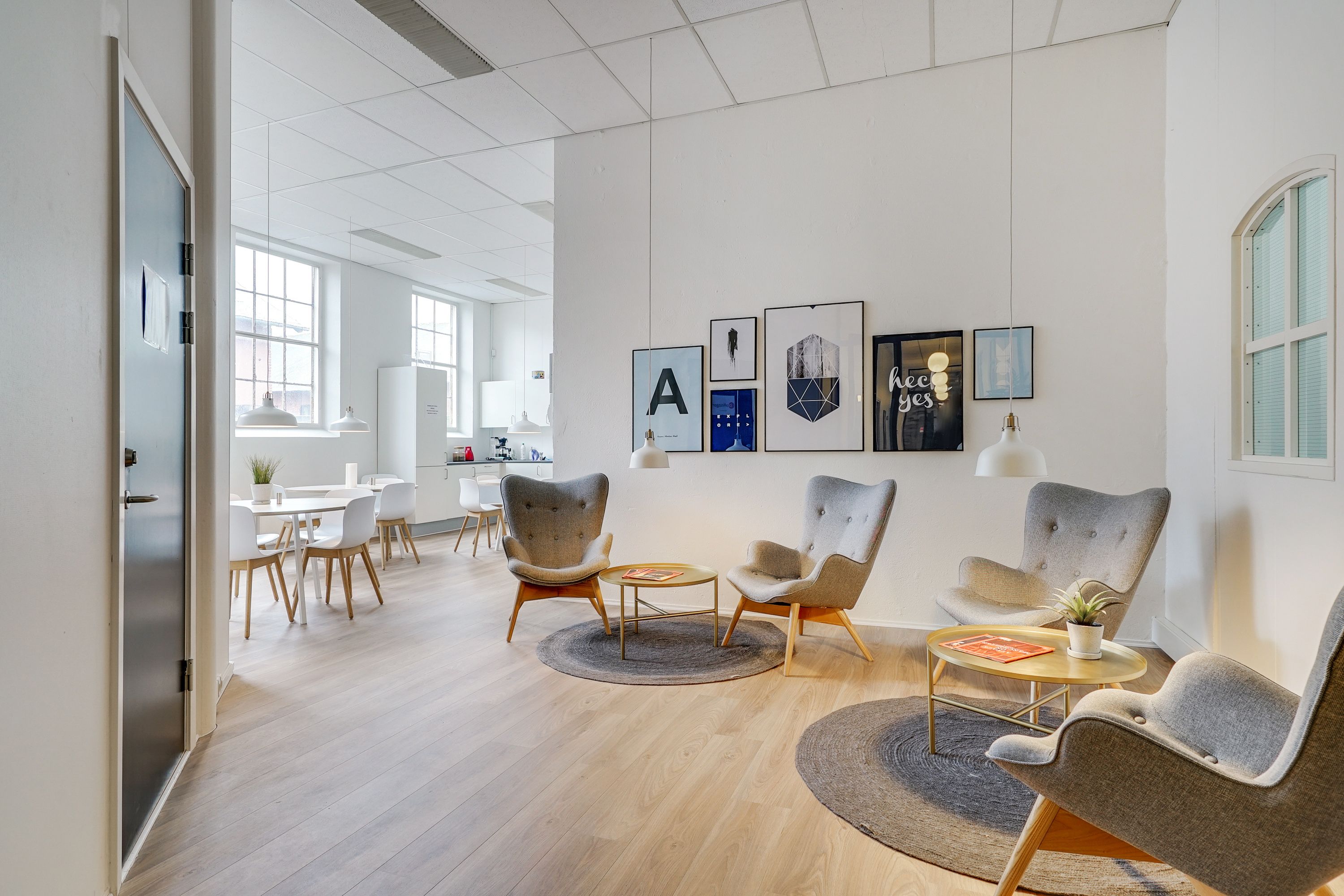 Kontor med højloft, højt til loftet hængende lysekroner, højt til loftet hængende billeder, moderne møbler og et stort bord