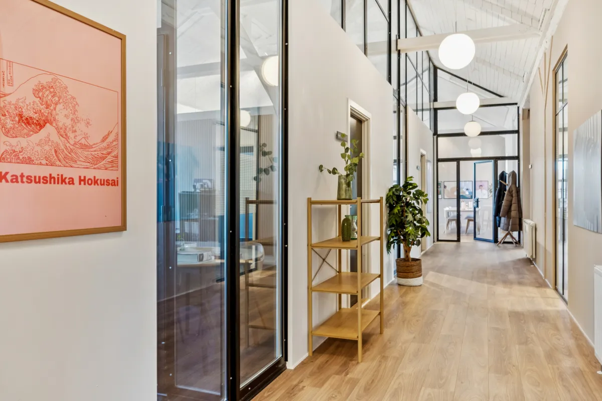 Kontorfællesskab med lyse vinduer, højt til loftet og hyggeligt indretning med plante og moderne indretning