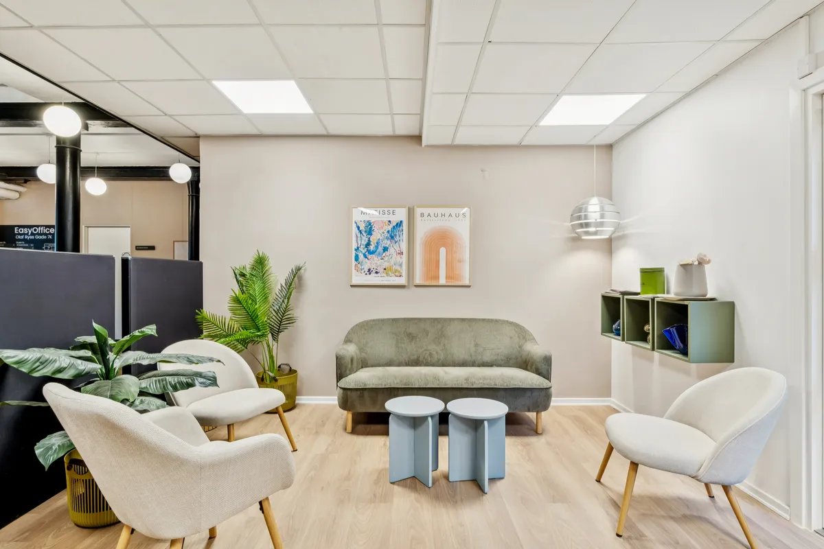 Kontorfællesskab med en lyse farvepalett, sofa og stolene og lyse loftslamper og lyse plantager