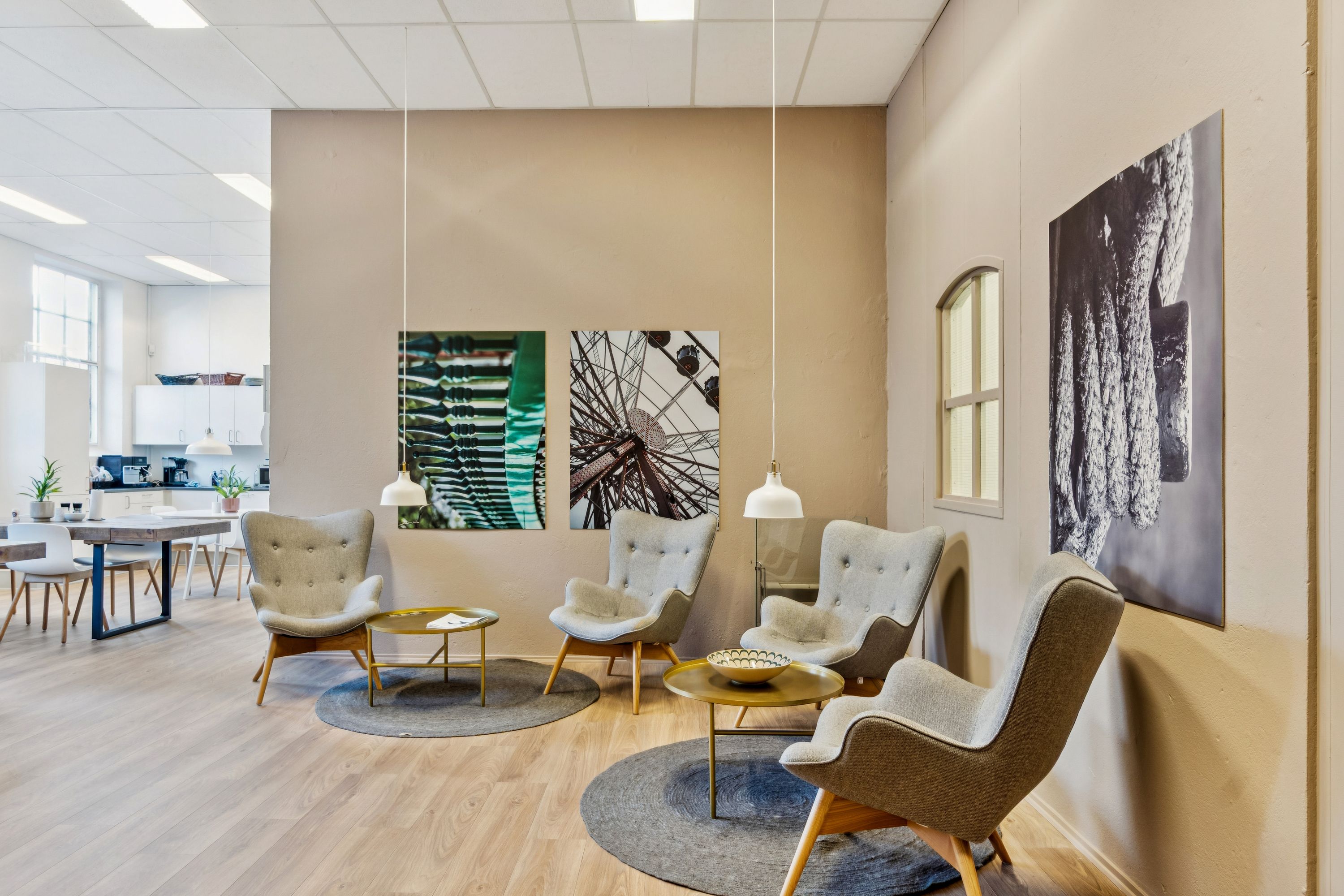 Kontorfællesskab med lyse lysekroner og smukke vægmalerier, flere læsestolhe og et bord med en skål på midten af gulvet