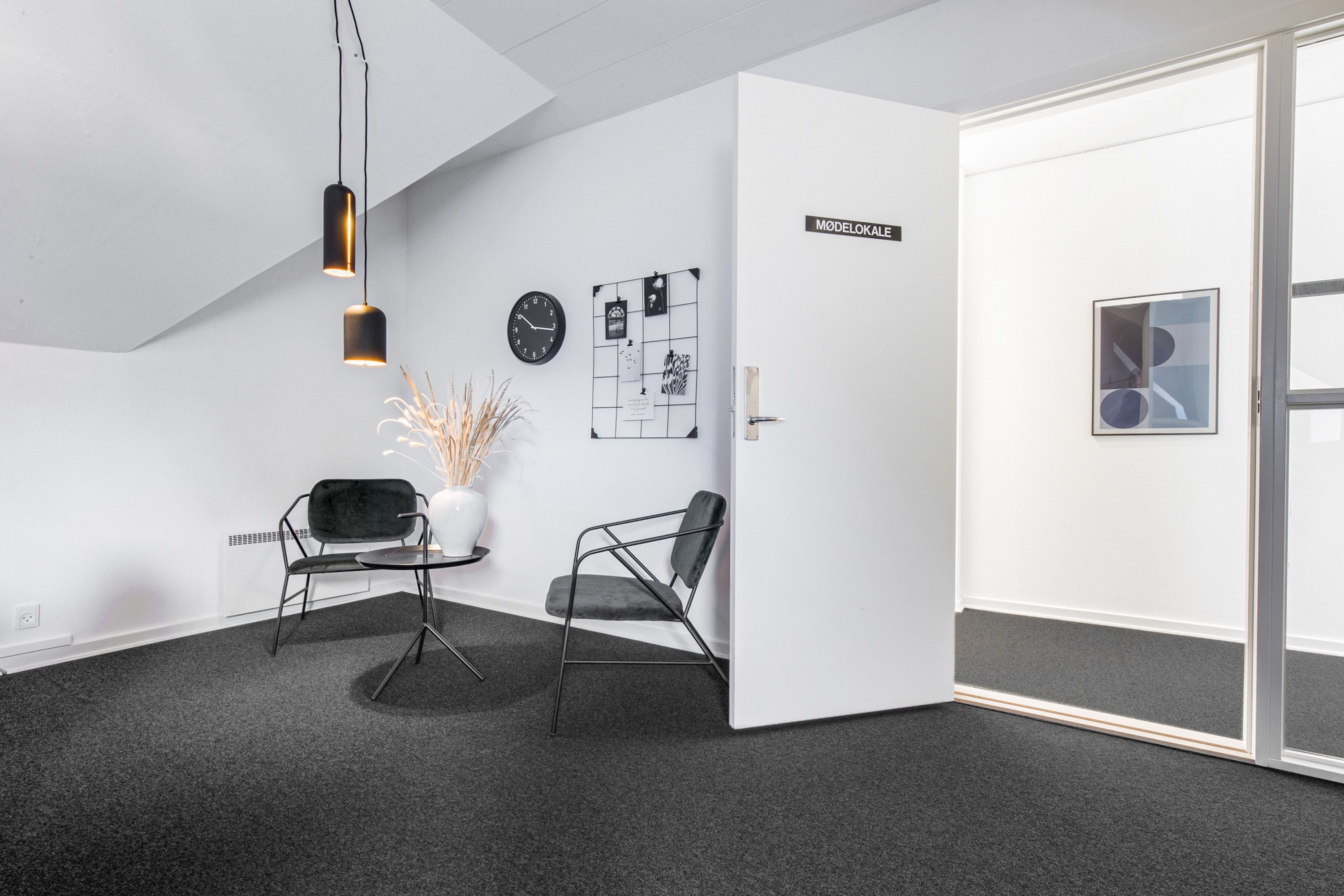 To stole og et bord med en vase, klokken 3:30, to lysekroner og et billede i en mørk ramme