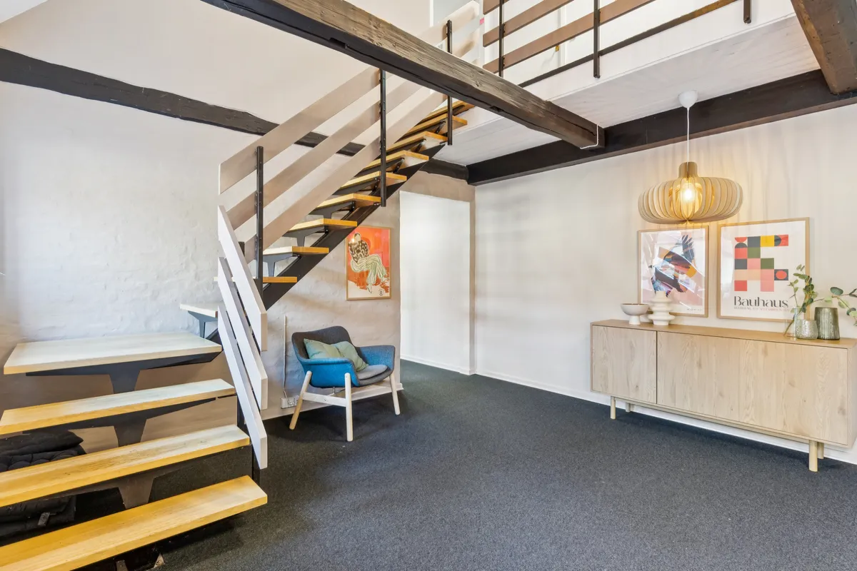 Inde i et moderne kontor er der et træklatretræ med et hyggeligt sæt sofa og lampe over en træbord og væg med kunstværker