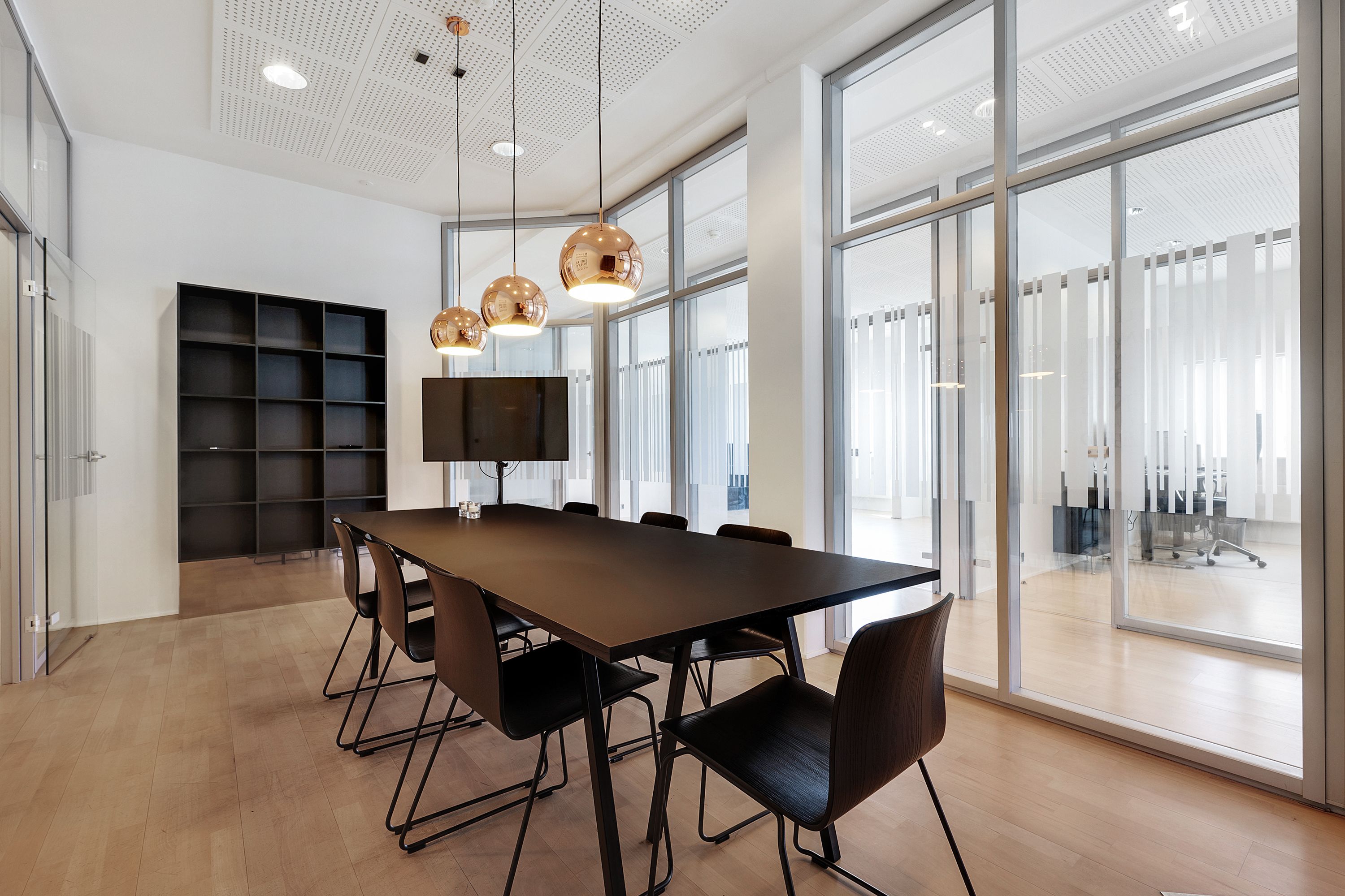 Kontorlokaler med store glasruder, en lang møbelrække og moderne møbler og en stol med høj ryglæn