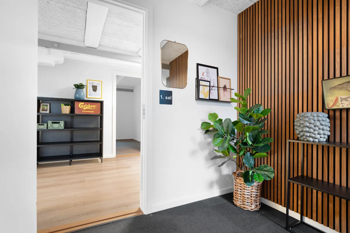 Kontorhal med højt loft, plante i kurv, væg med træbeklædning og møbler med minimalistisk design