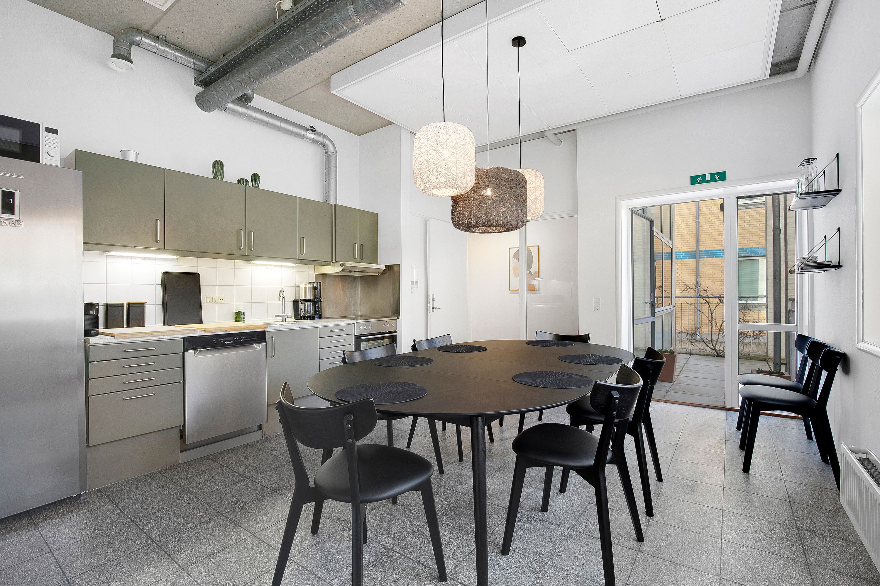 Et moderne køkken med en stor rund træbord, moderne møbler og en lukket dør til terrassen