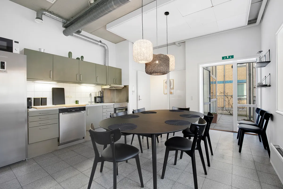 Et moderne køkken med en stor rund træbord, moderne møbler og en lukket dør til terrassen