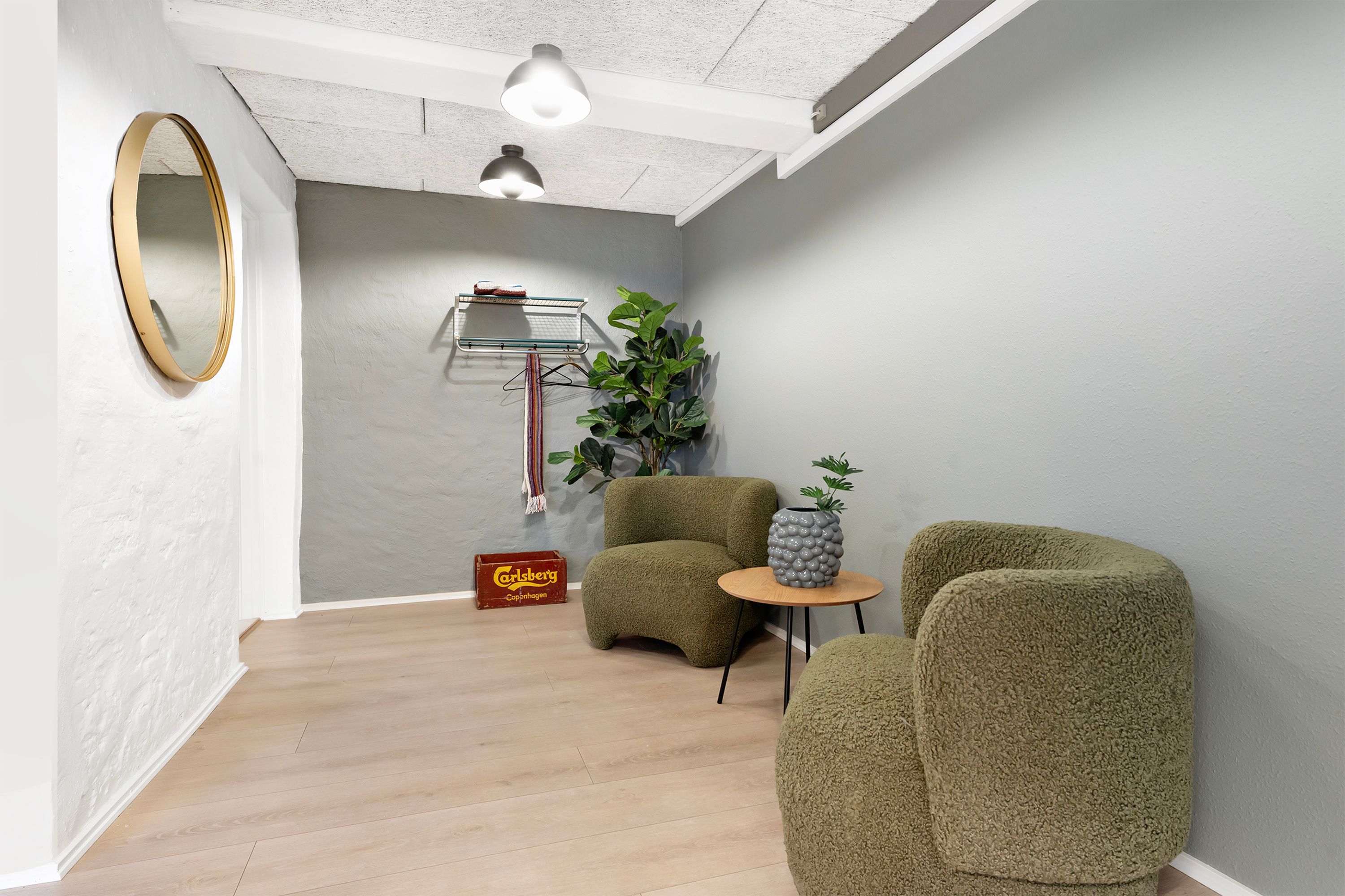 Foto af tæt besat, luksuriøs lobby med to grå, bølgete sæder og et træbord med vase på det