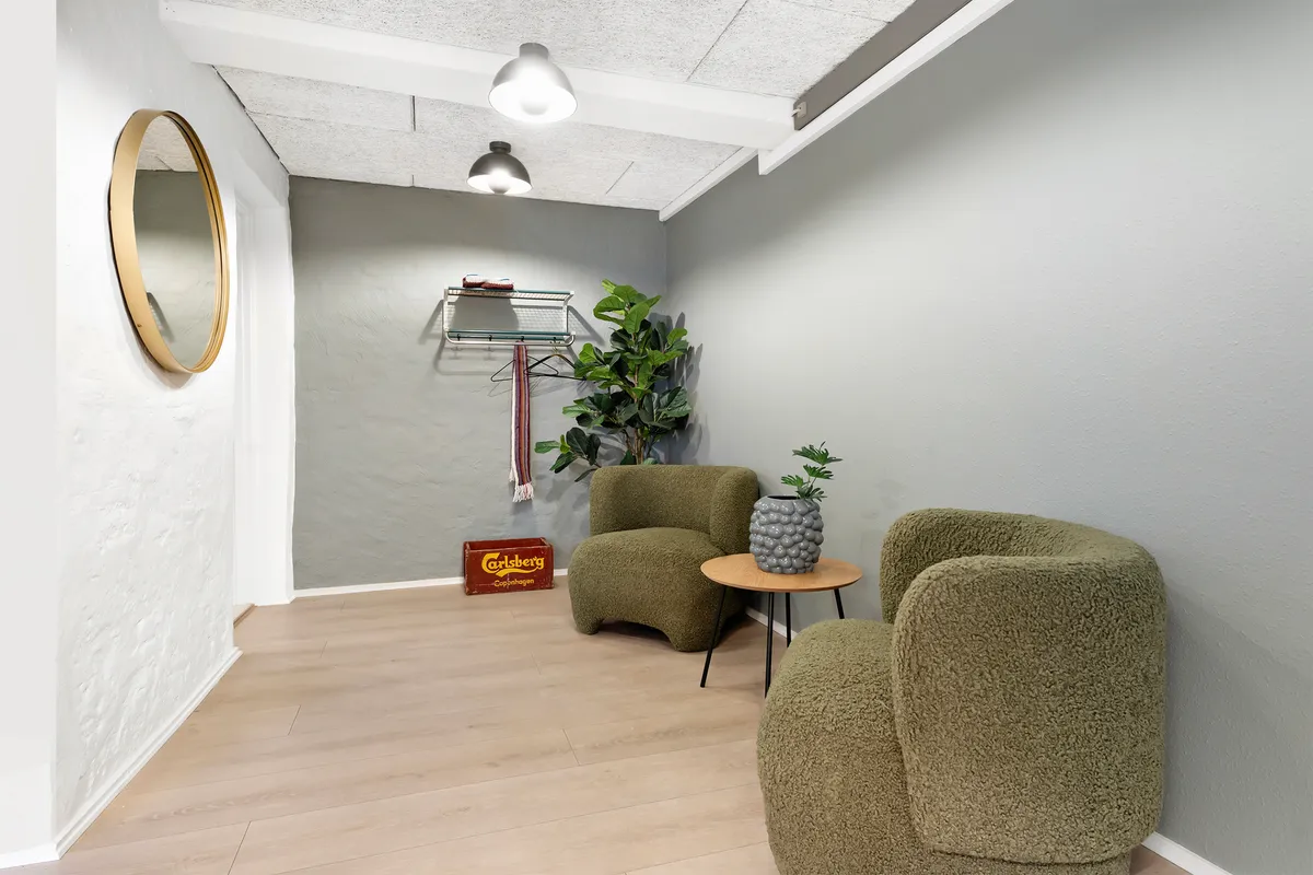 Foto af tæt besat, luksuriøs lobby med to grå, bølgete sæder og et træbord med vase på det