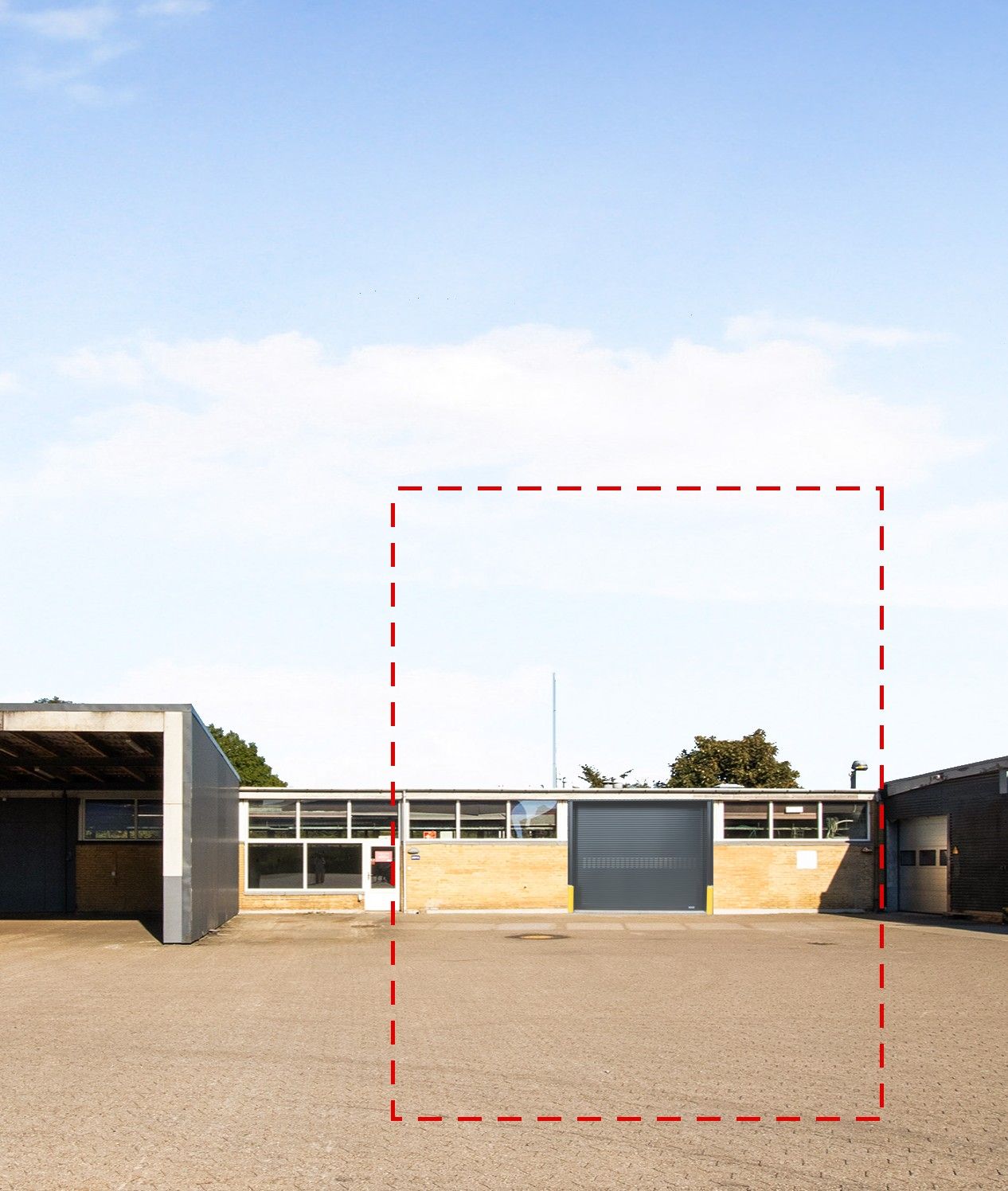 Lager med garagedør og vinduer på den ene side og en stor tom plads på den anden side