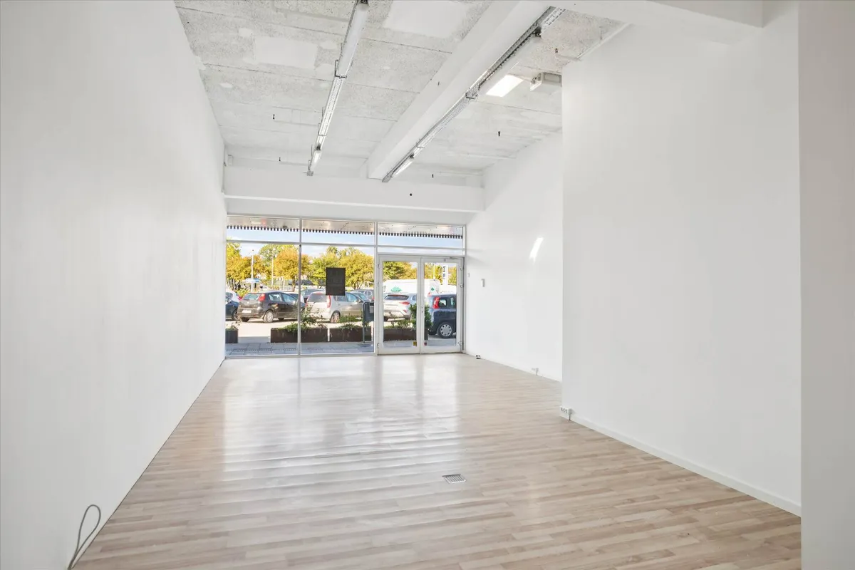 Lejemålet har en stor, lys og rummelig indgangsparti med trægulv og hvide vægge samt glasdøre