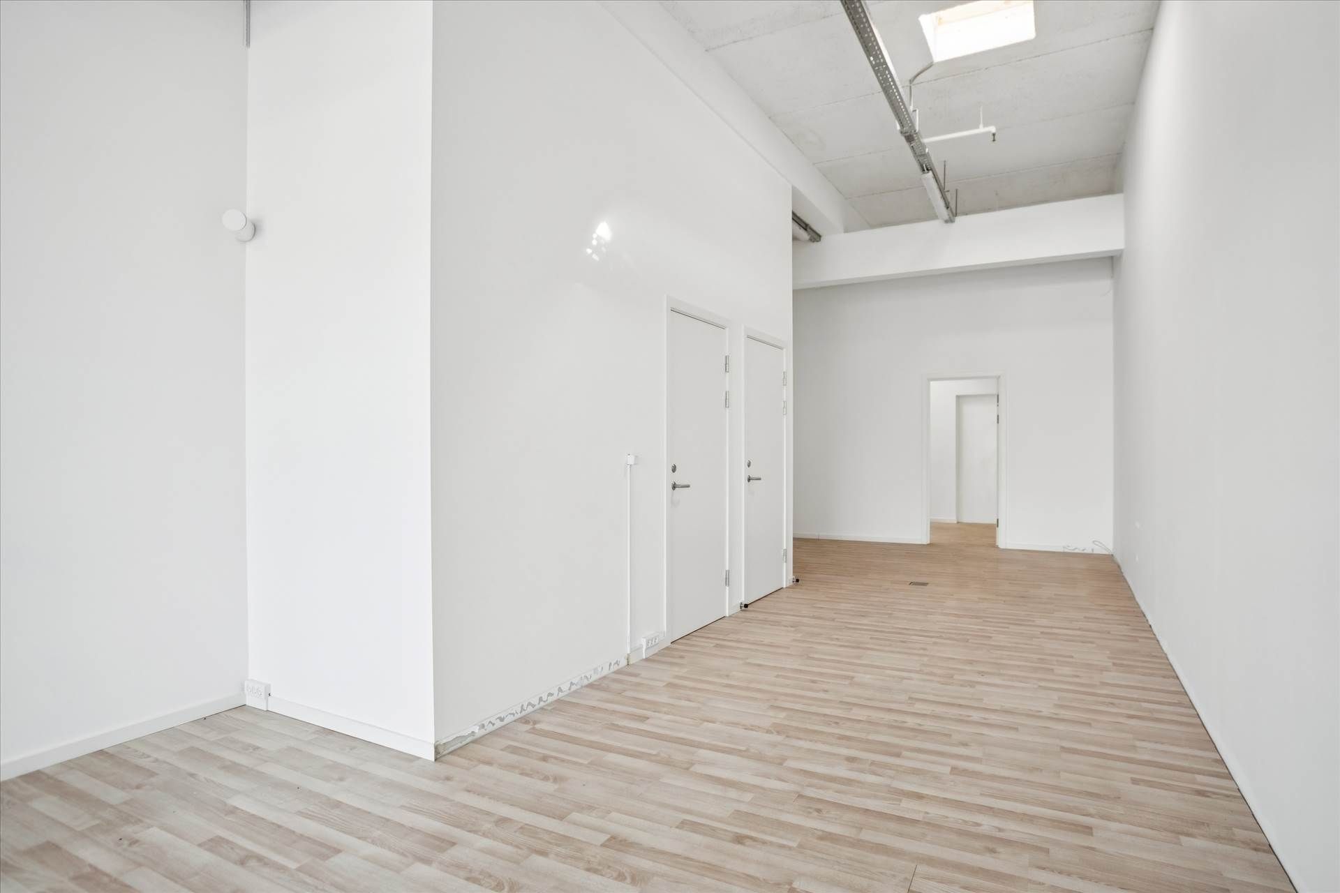 Lejlighed med to rum og et badeværelse. Lejlighed med højloft og moderne design. Værelse med hvide vægge og trægulv.