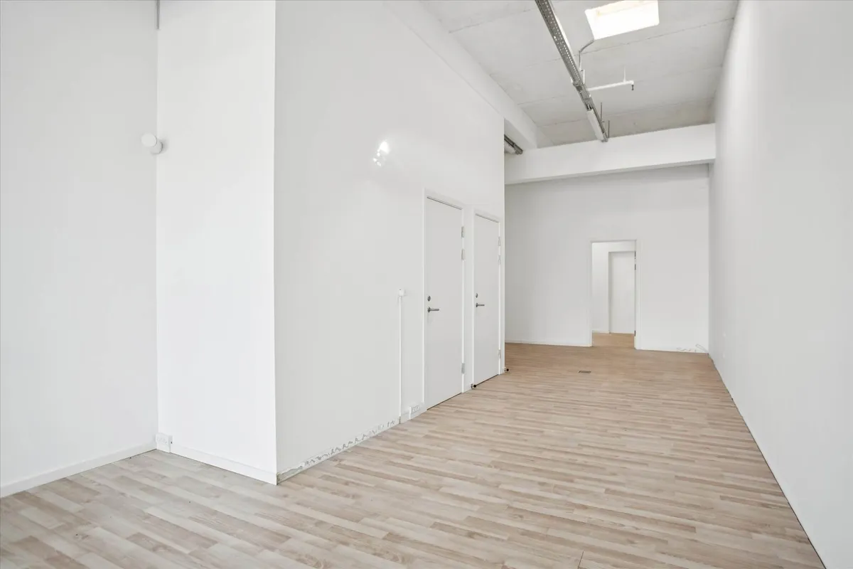 Lejlighed med to rum og et badeværelse. Lejlighed med højloft og moderne design. Værelse med hvide vægge og trægulv.