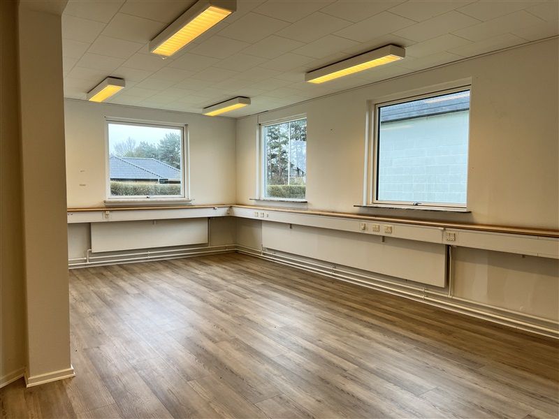 Moderne kontor med tre vinduer, hvide vægge og tre store lysekroner. Væggen har en række stikkontakter og en hvid