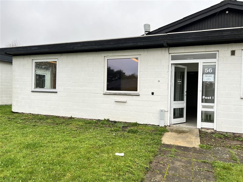 Et moderne, hvidt kontorhuse med nummer 56 og to store ruder samt åben dør