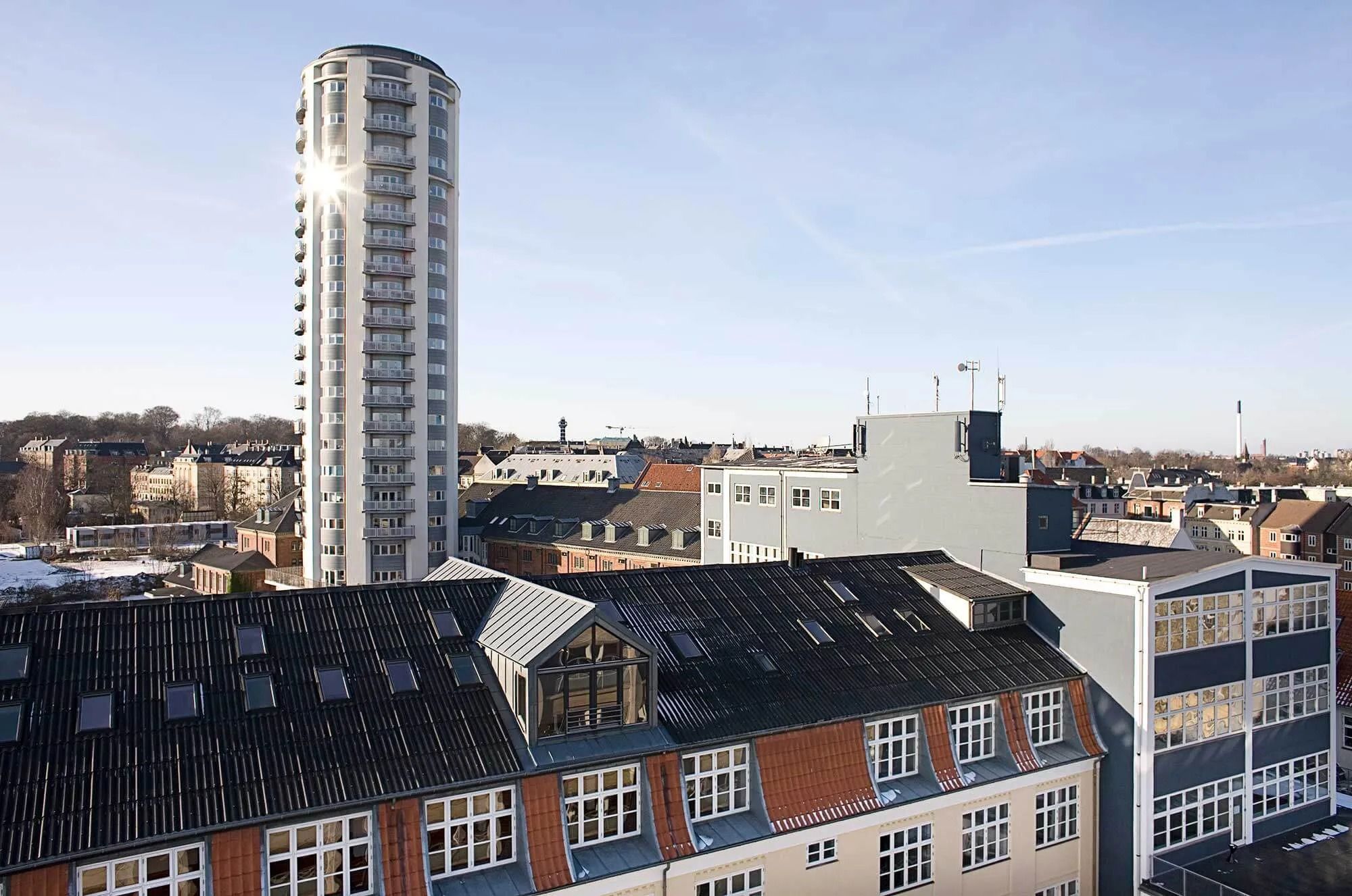 Byudsigt med et højt kontorhus og andre bygninger i baggrunden, der er dækket af sne