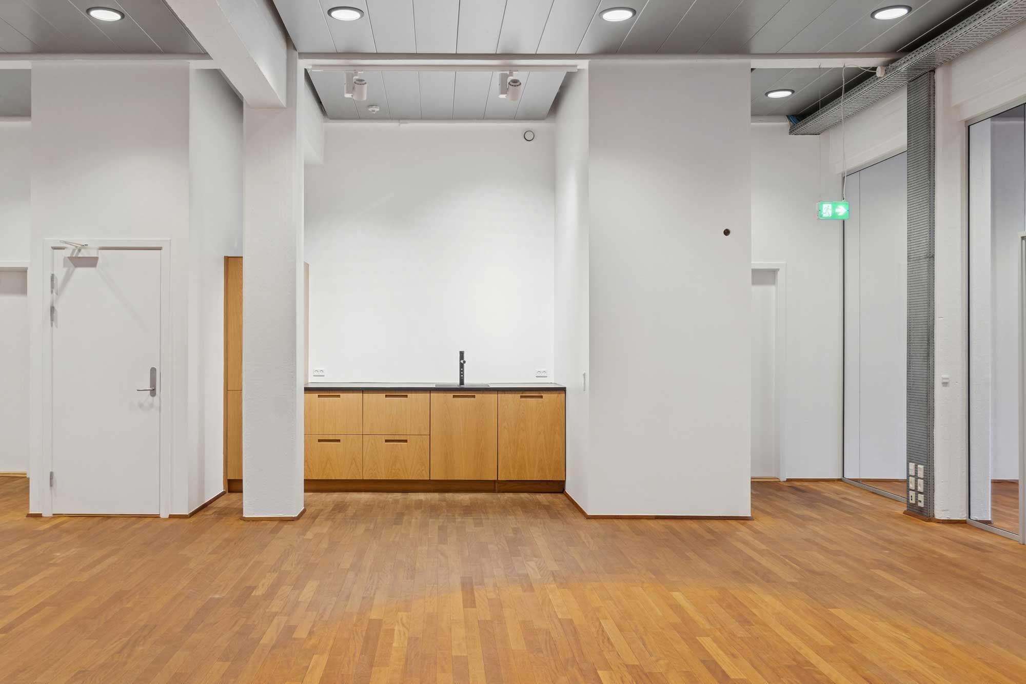 Et stort, rensvejs og moderne kontor med lys, hvidt loft, gulv og vægge samt lyse og funktionelle møbler