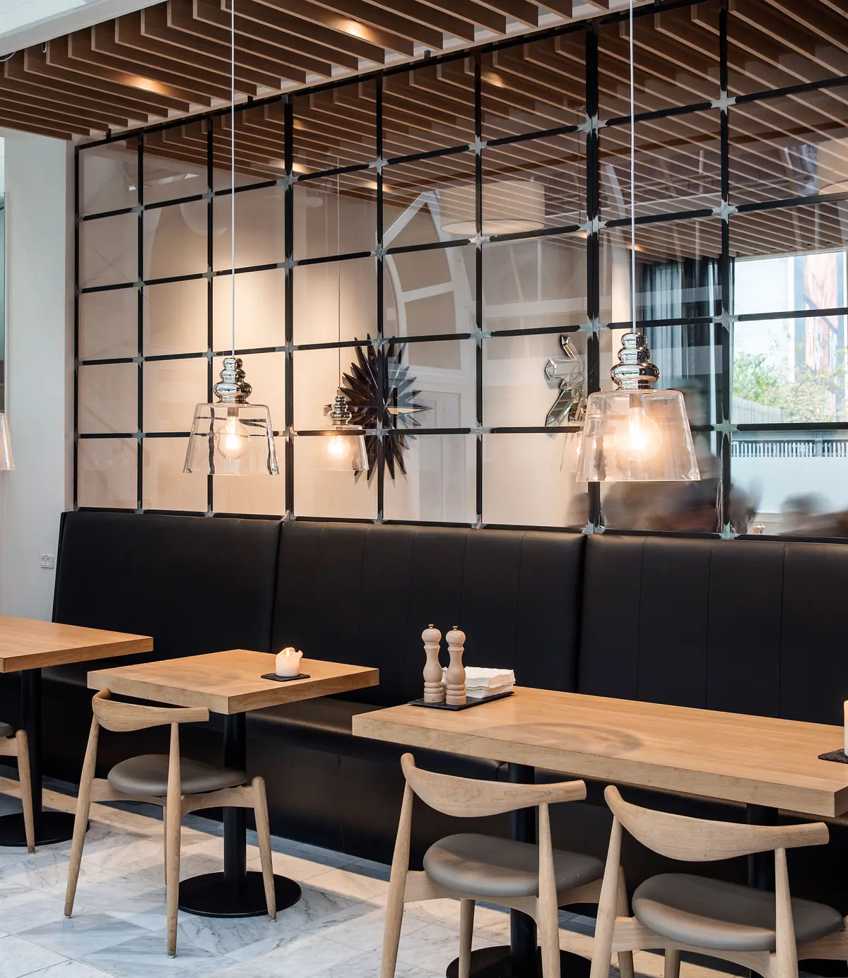 Moderne møbler og lyse træborde i en elegant indretning med lysekroner og spejlvægge