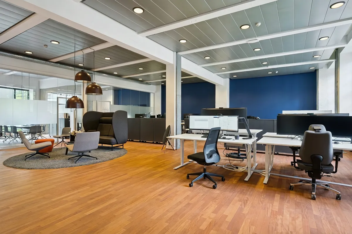 Kontor med lyse gulve, moderne møbler og tre sammensatte arbejdsborde med computere