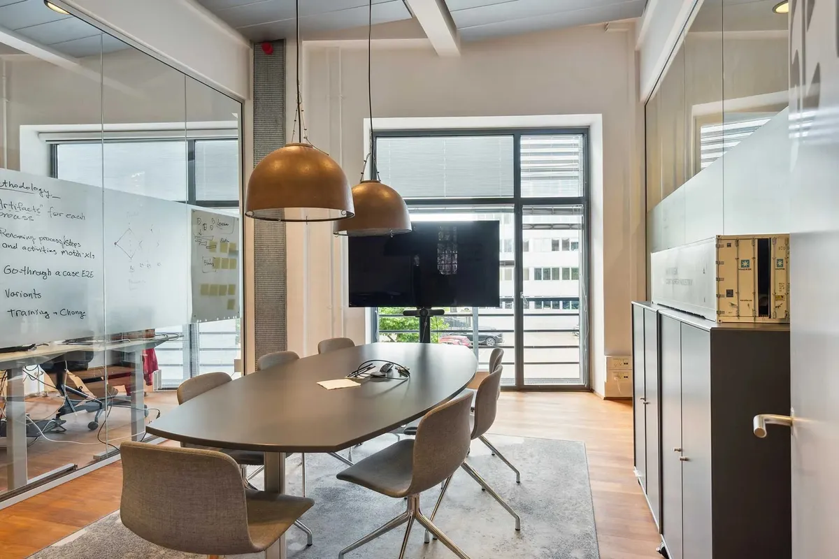 Rundt mødebord med stole i et moderne kontor med skrivepinde og noter på væggen