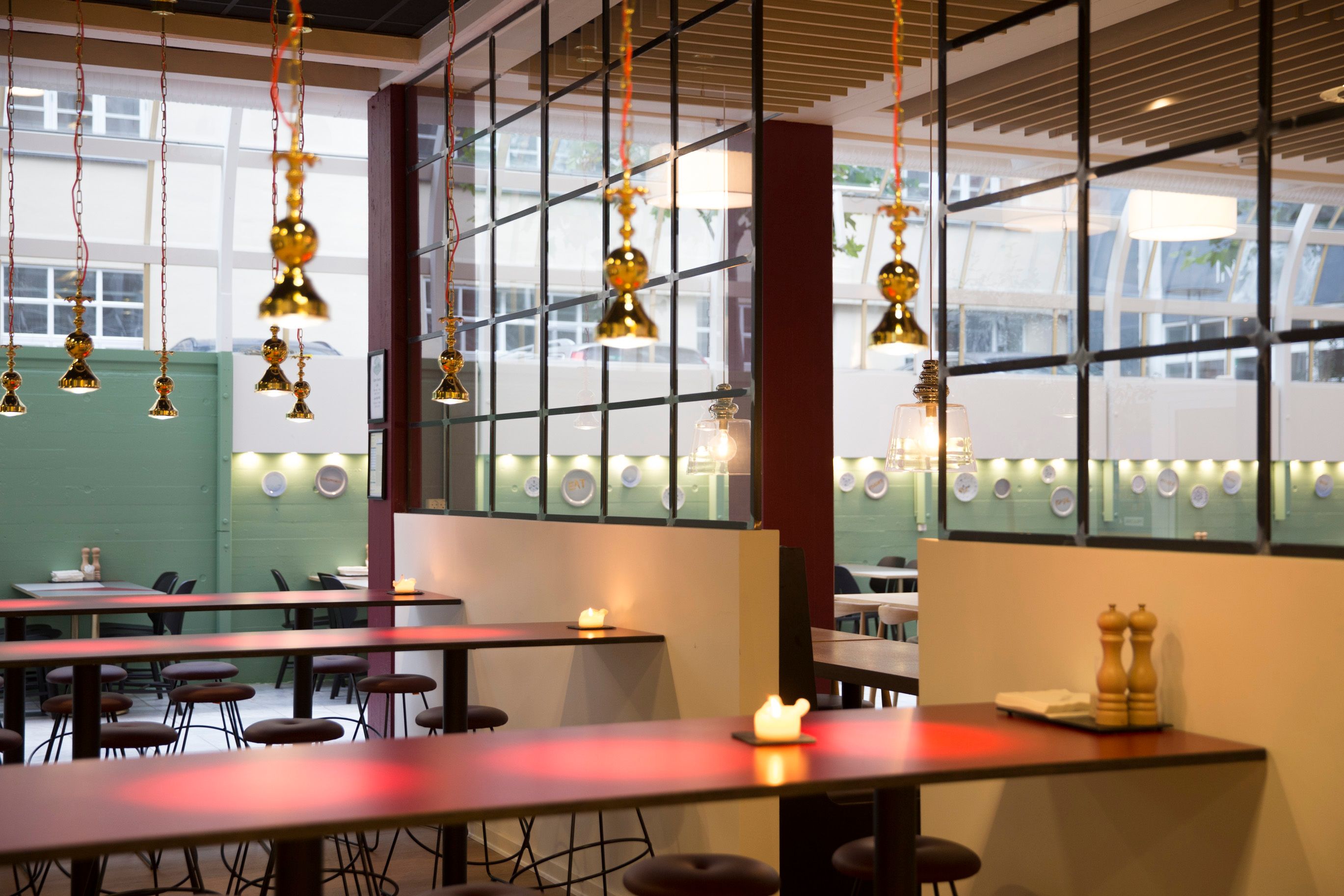 Kontorlokation med mørkerøde borde, gule lysekroner og høje vinduer på Vesterbrogade i København V.