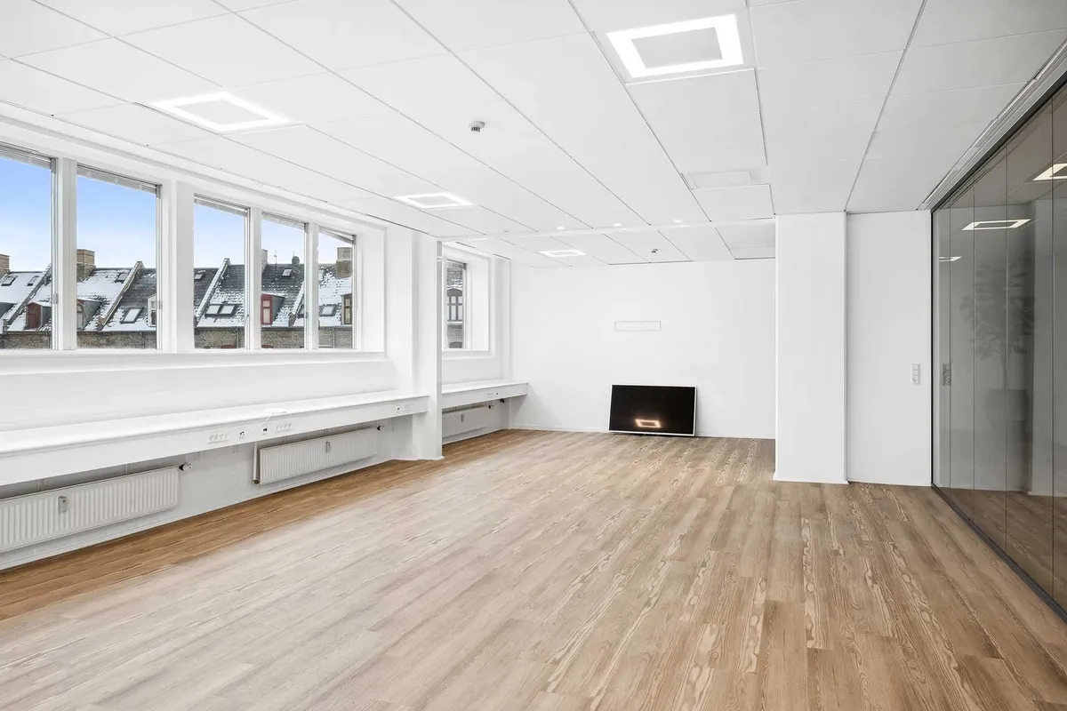 En stor kontorbygning med højloftede værelser og lyse trægulve. Der er store vinduer, som lade sollys strømme ind, og der er