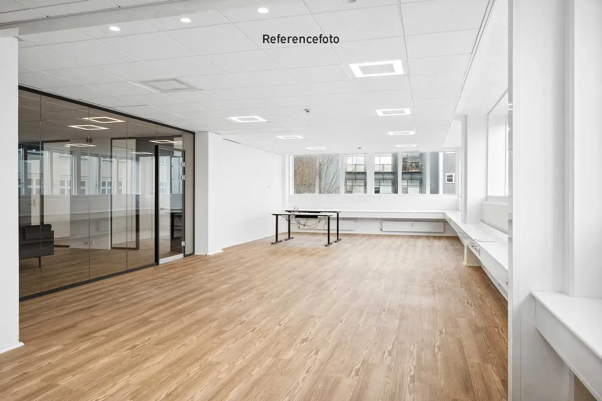 Moderne kontorrum med højt hvidt loft, massivt trægulv og glasdøre, træbord med kabel og hvide vægge med indlejrede vinduer