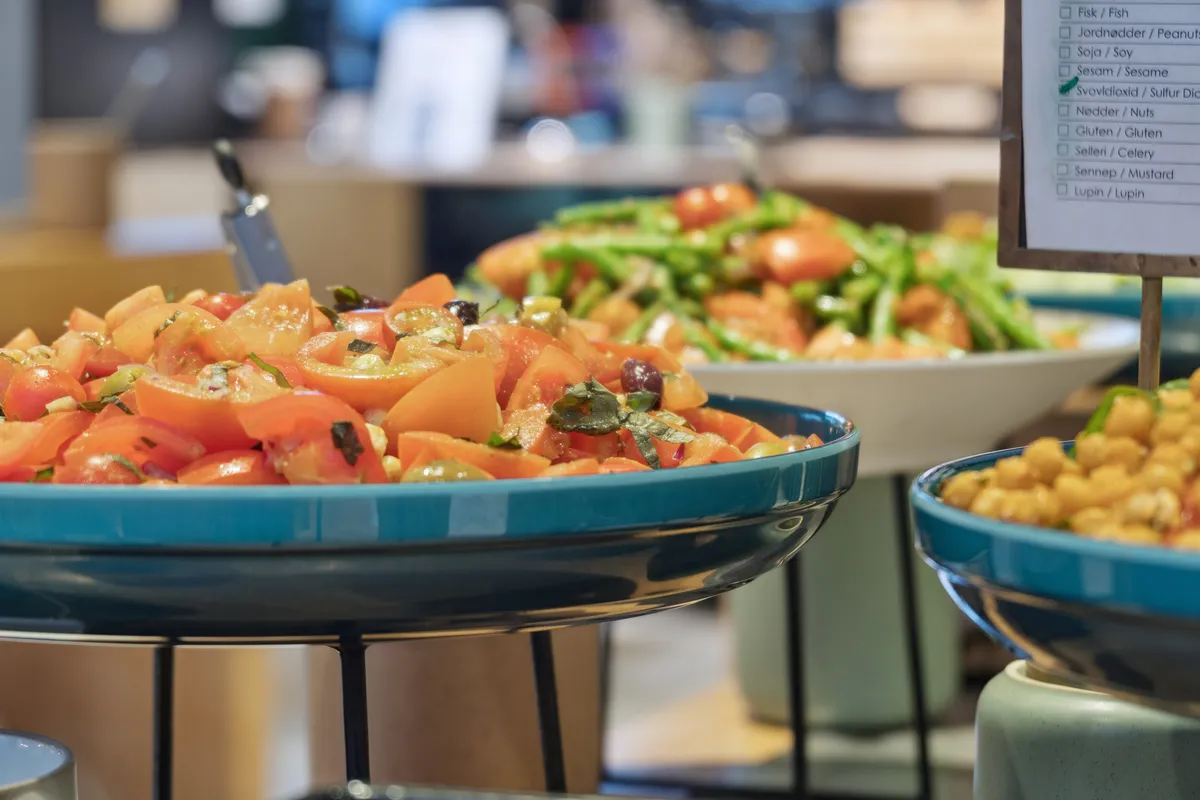 Moderne kontor med en serveringsbord med tomatsalat, grønbønner og en anden skål med valnødder