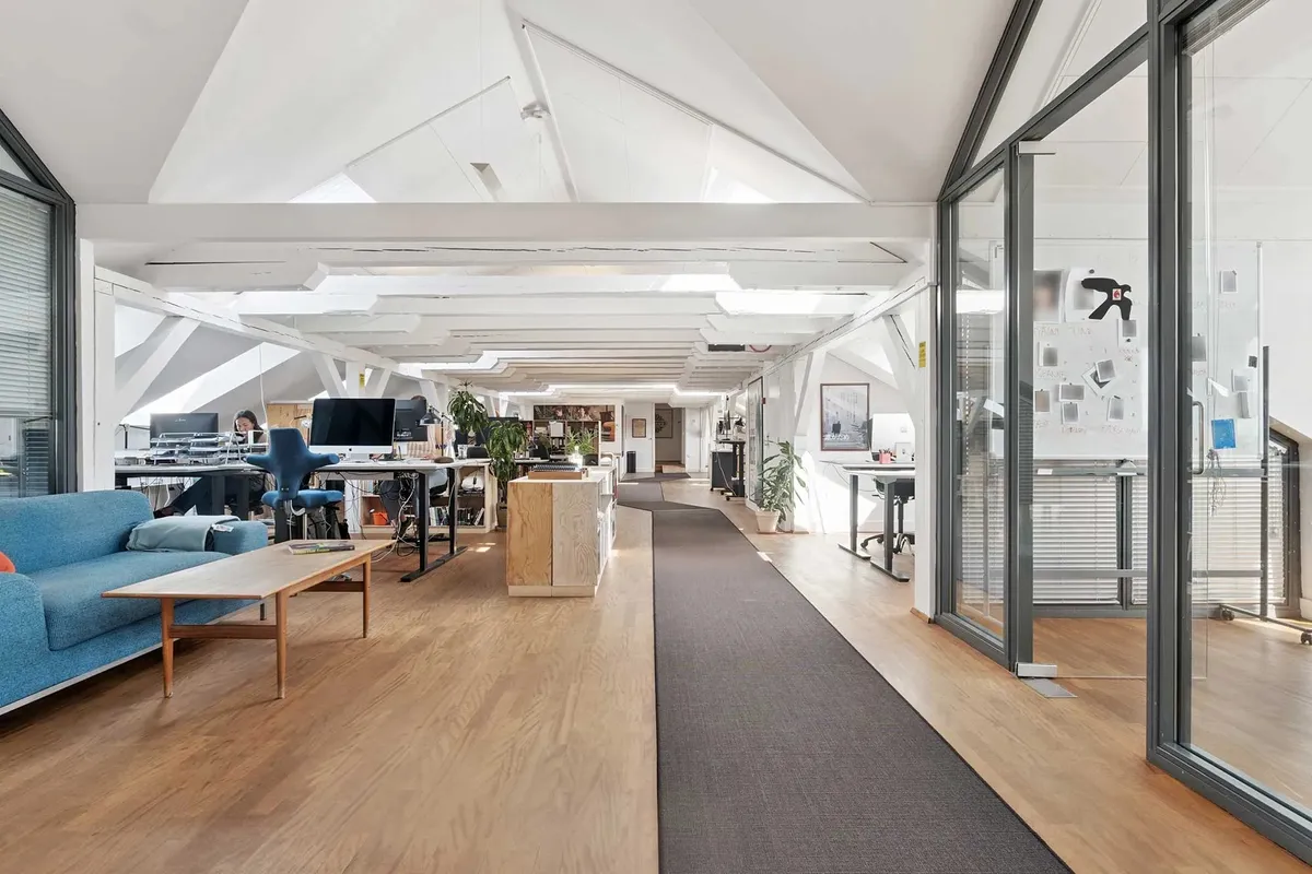 Et moderne kontor med højloft, trægulve og høje vinduer med store glasruder