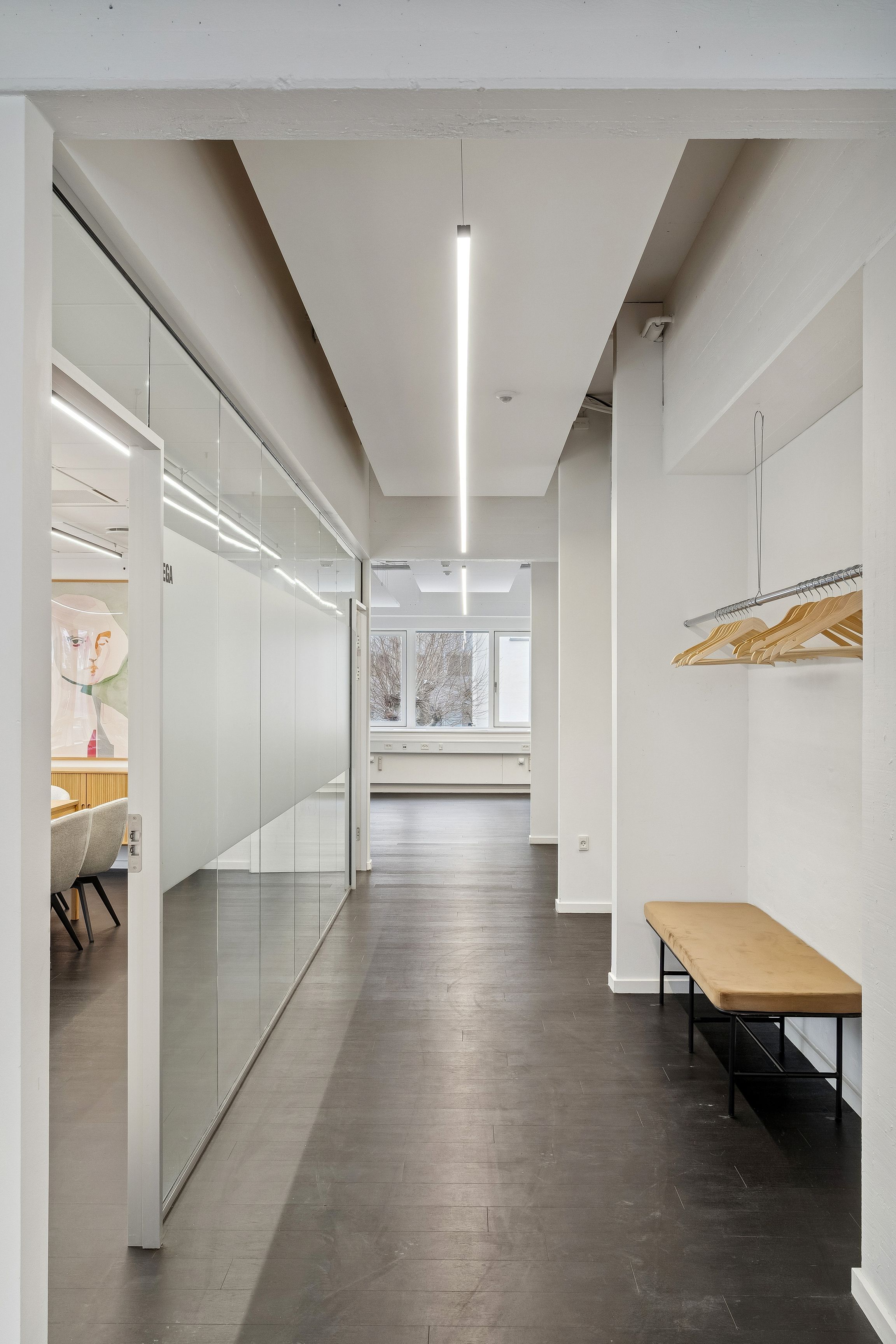 Moderne kontor med højloft og glasvægge, træhylde med træhængere, lysekroner og bekvemme møbler i minimalistisk stil