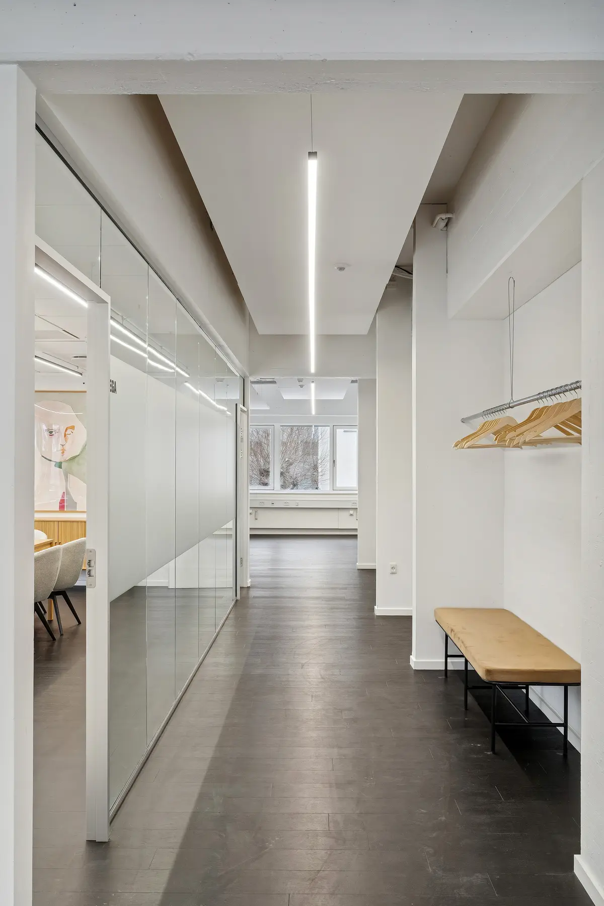 Moderne kontor med højloft og glasvægge, træhylde med træhængere, lysekroner og bekvemme møbler i minimalistisk stil