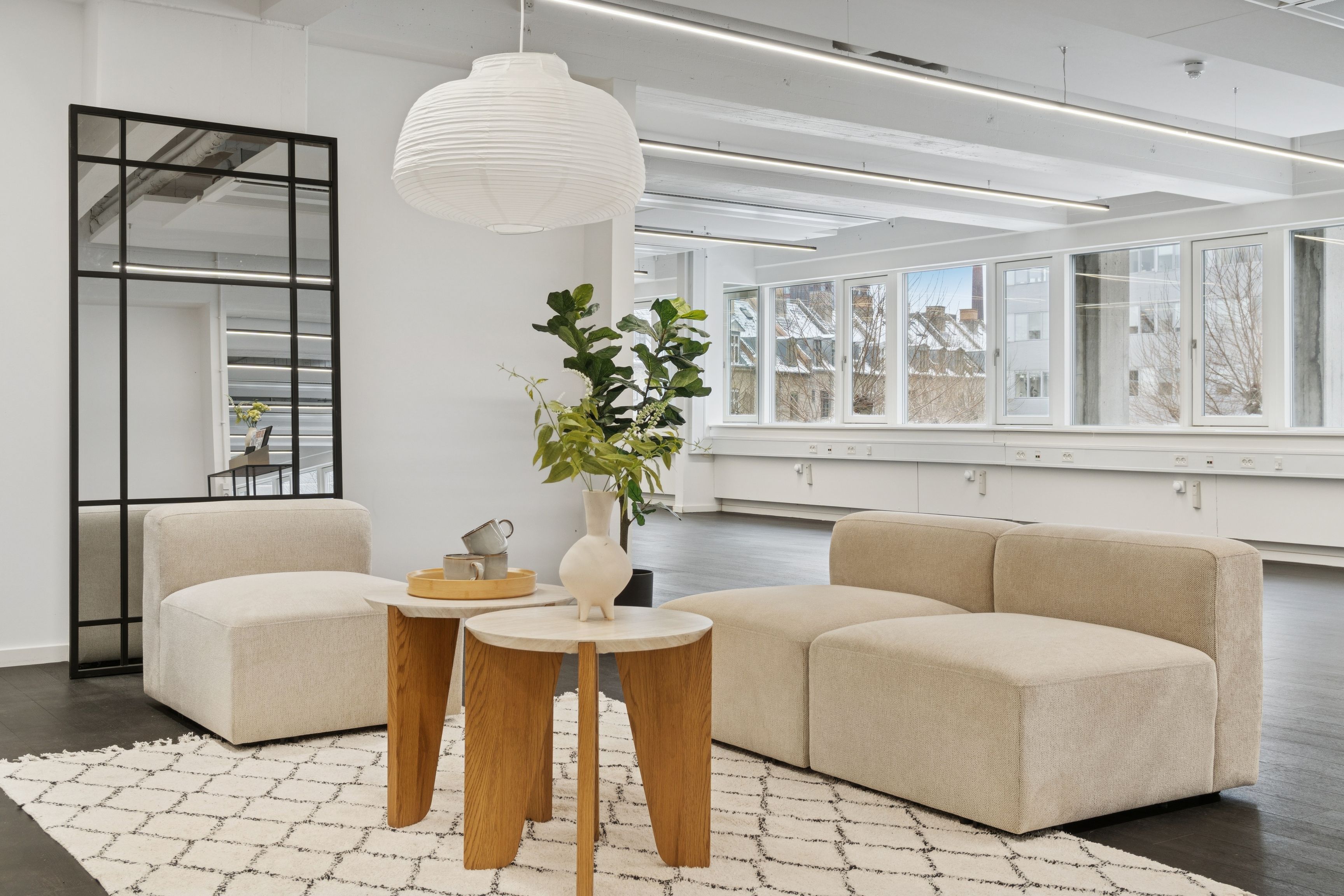 Kontor til leje på Vesterbrogade 149 med lyse vinduer og lyse loftsbånd. Møbler med lyse farver og en plante i et hvidt fad. Et hvidt sengehoved reflekteres i et spejl