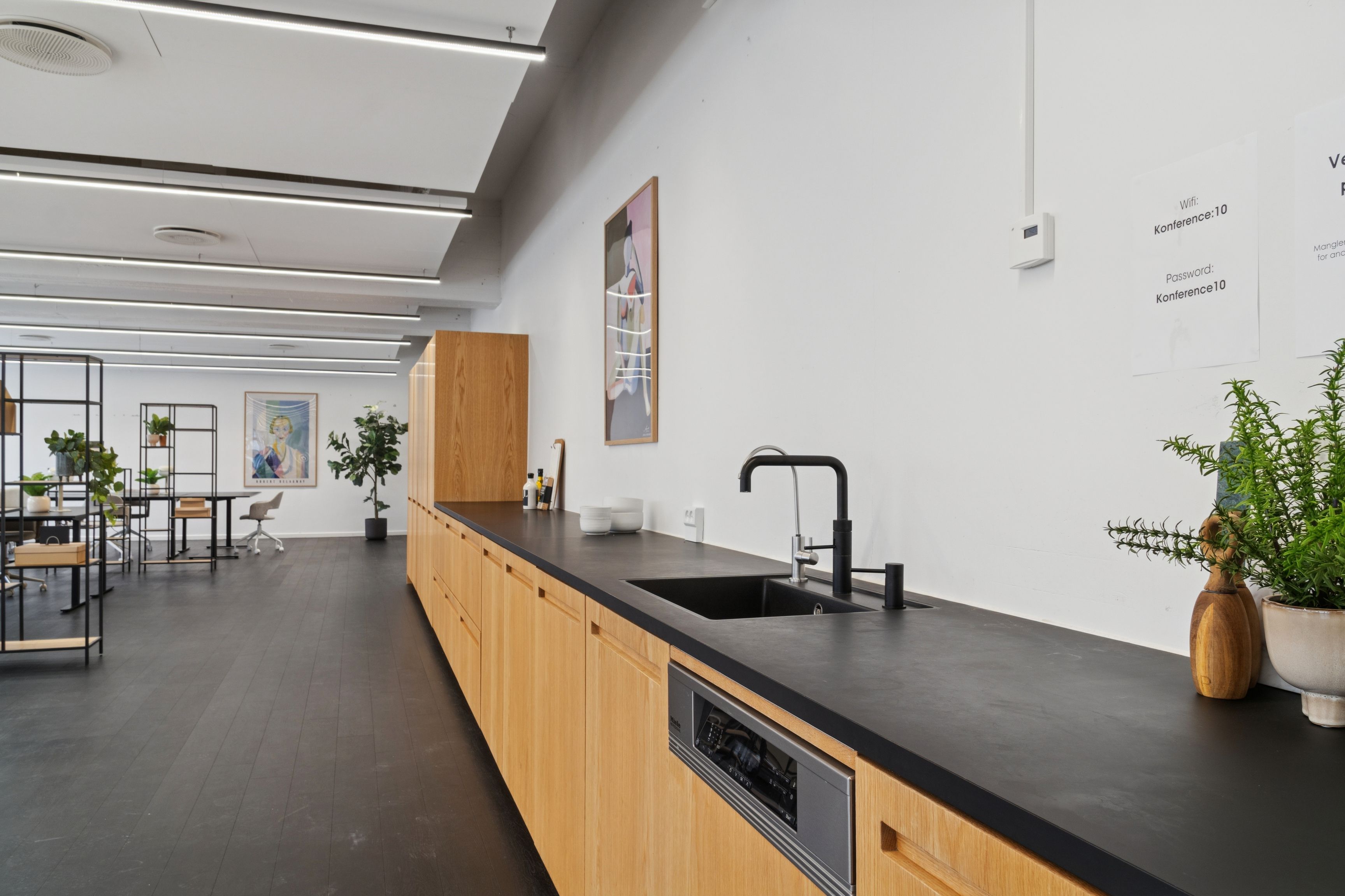 Kontor med lyse lofter, moderne køkken med sort bordplade, høj terrasse og lyse loftsvinduer samt kunst på væggen