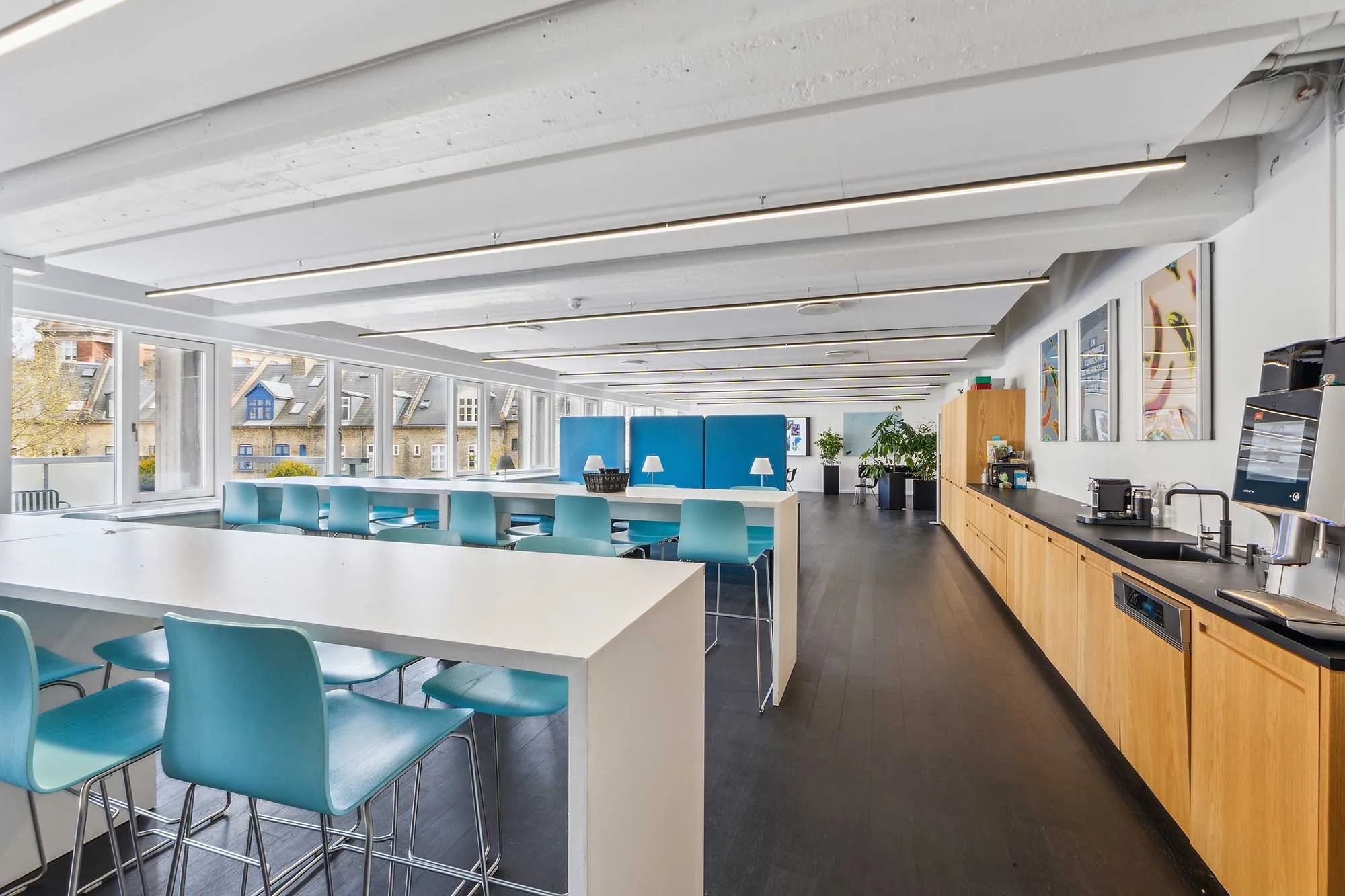 Stort, lyst kontor med moderne møbler, gulve og lysekroner, samt udsigt til byens gader