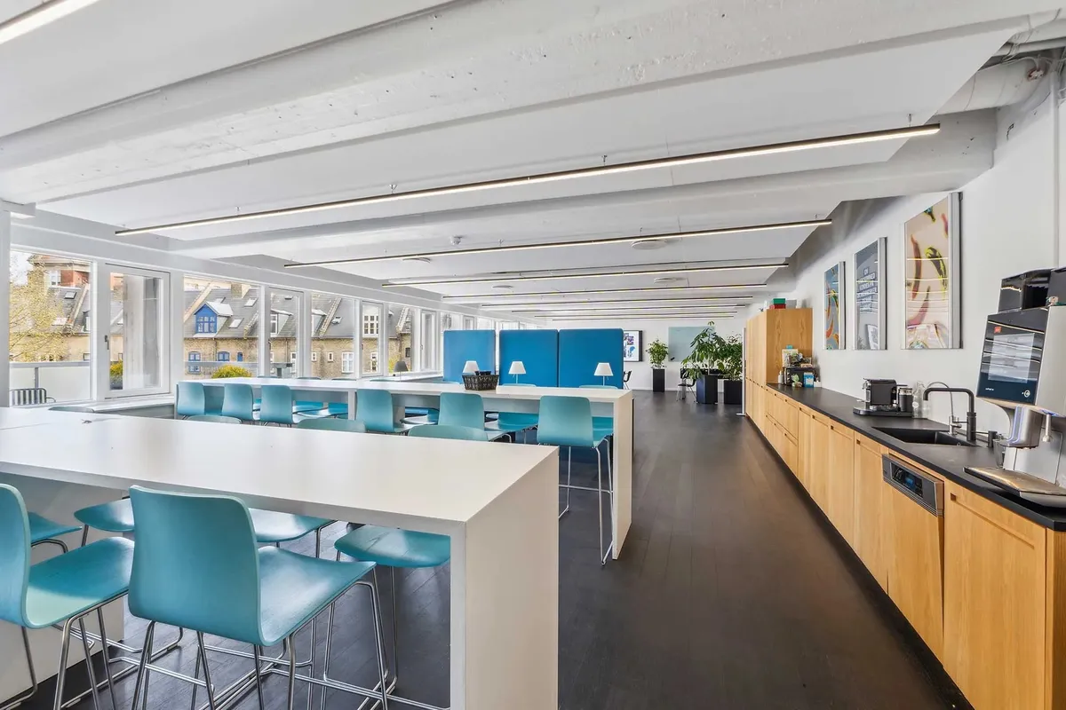 Stort, lyst kontor med moderne møbler, gulve og lysekroner, samt udsigt til byens gader