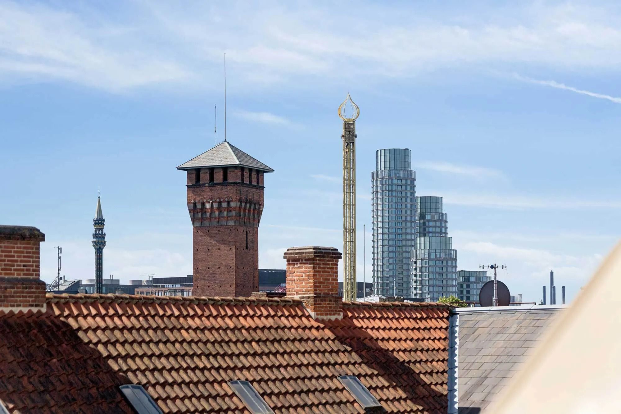 København med røde tag og tårne i baggrunden, højre side er moderne bygning, og venstre side er klassisk bygning